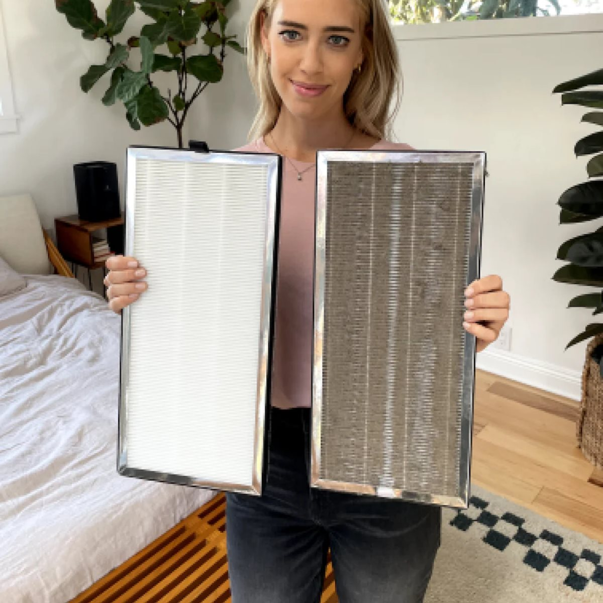 Vrouw houdt schone en vuile luchtfilters vast. Achtergrond met bed, plant en raam.