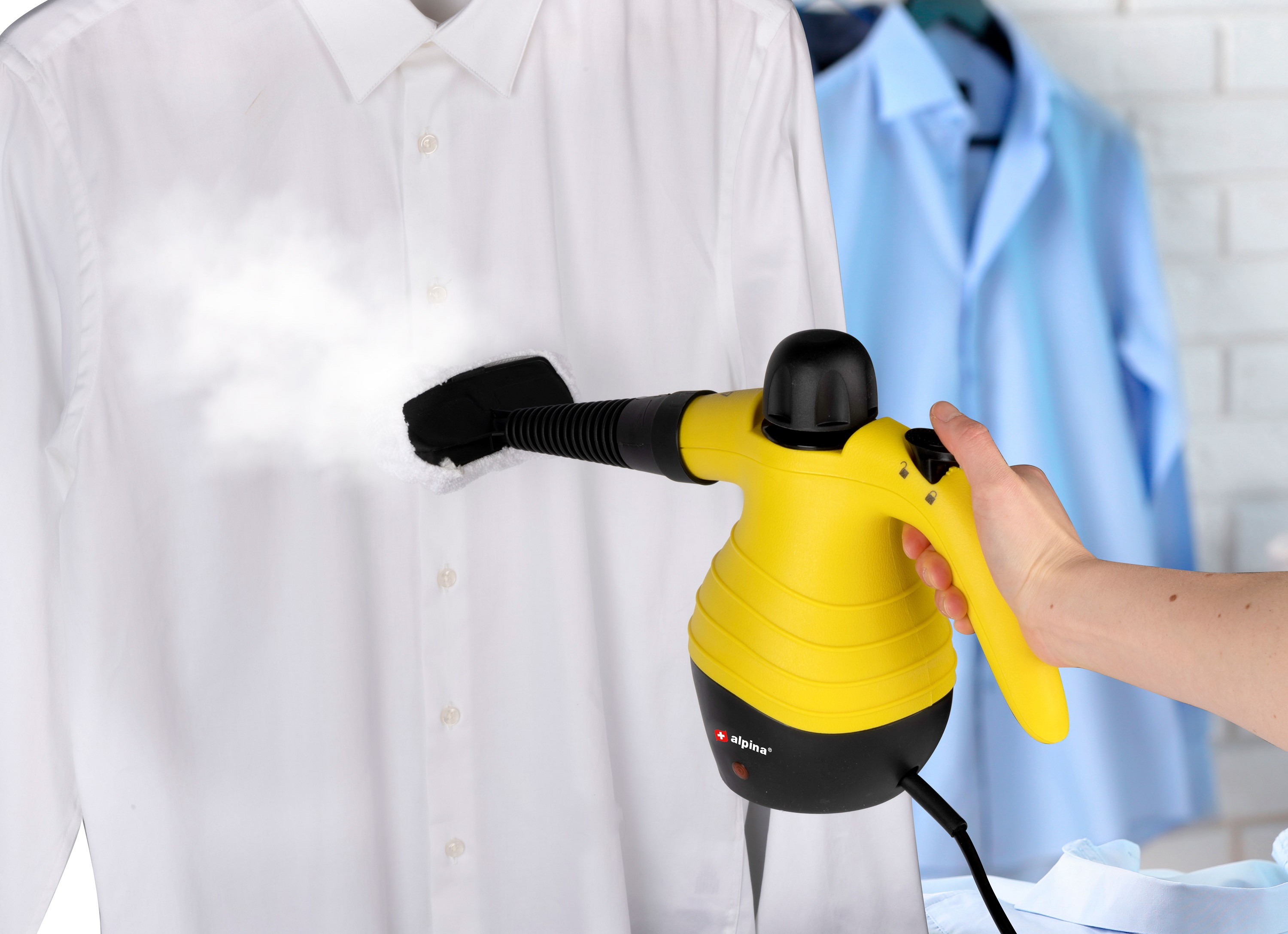 Een persoon stoomt een wit overhemd met een handheld stoomreiniger, op een hanger.