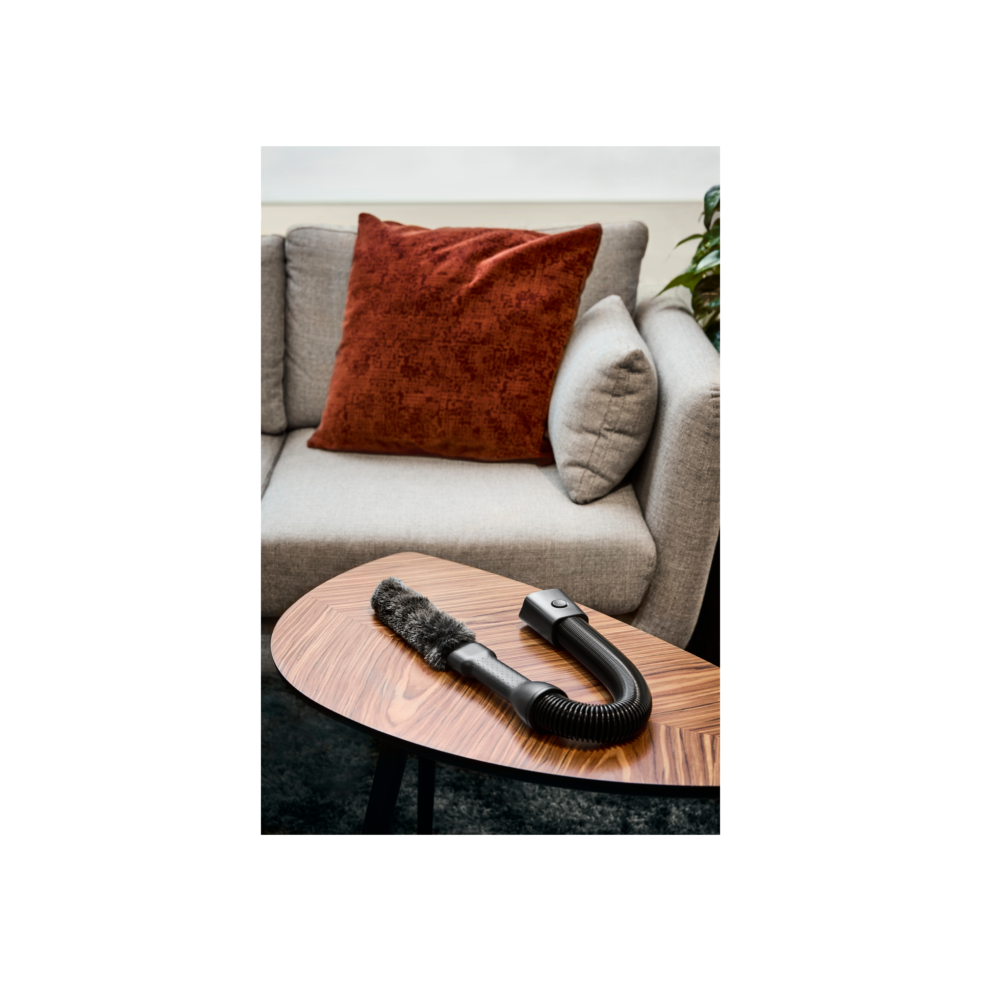 Końcówka do odkurzacza na drewnianym stole. Szara sofa i poduszka w tle.