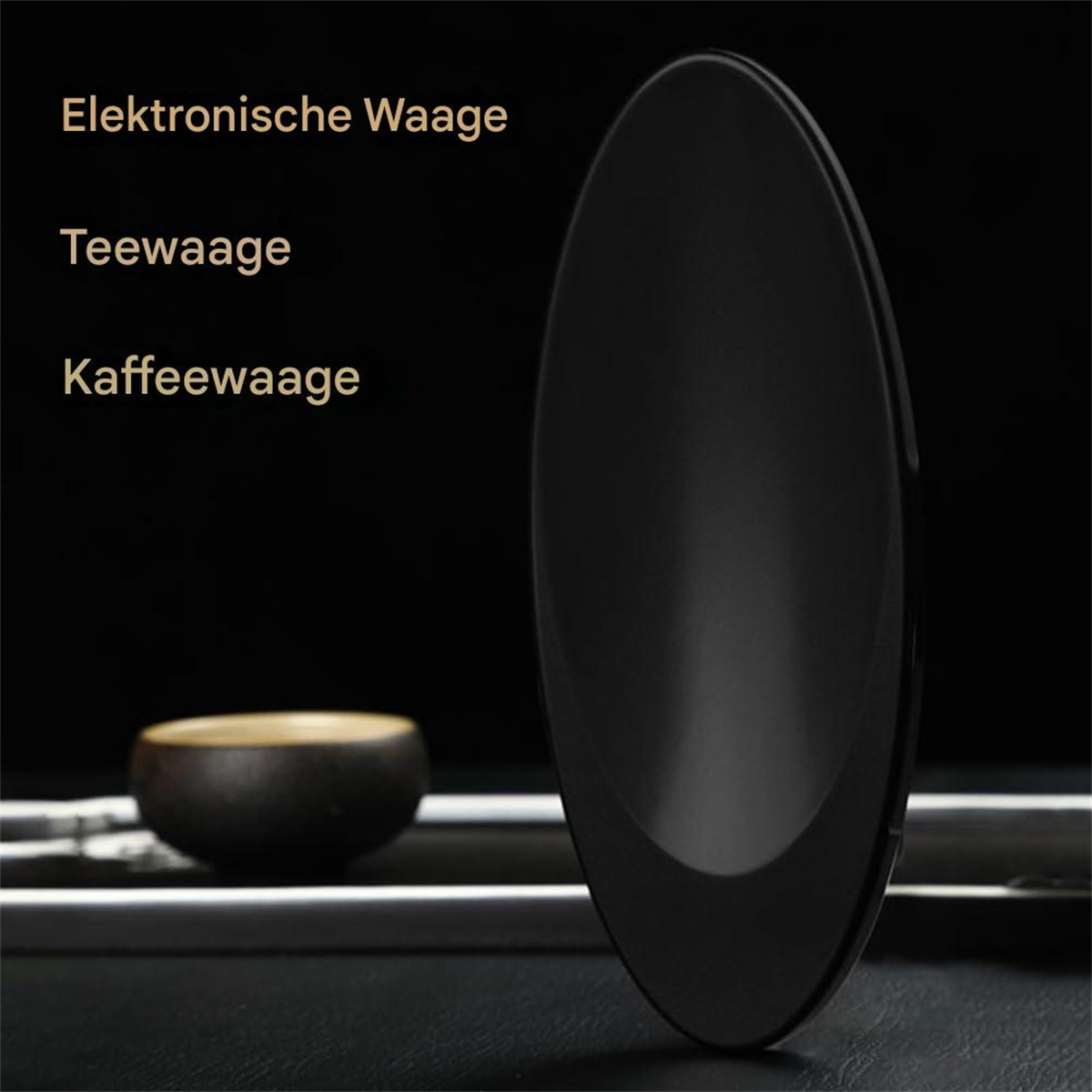 Eine schwarze, ovale Digitalwaage mit deutschem Text. Eine kleine Schüssel steht daneben auf schwarzem Untergrund.