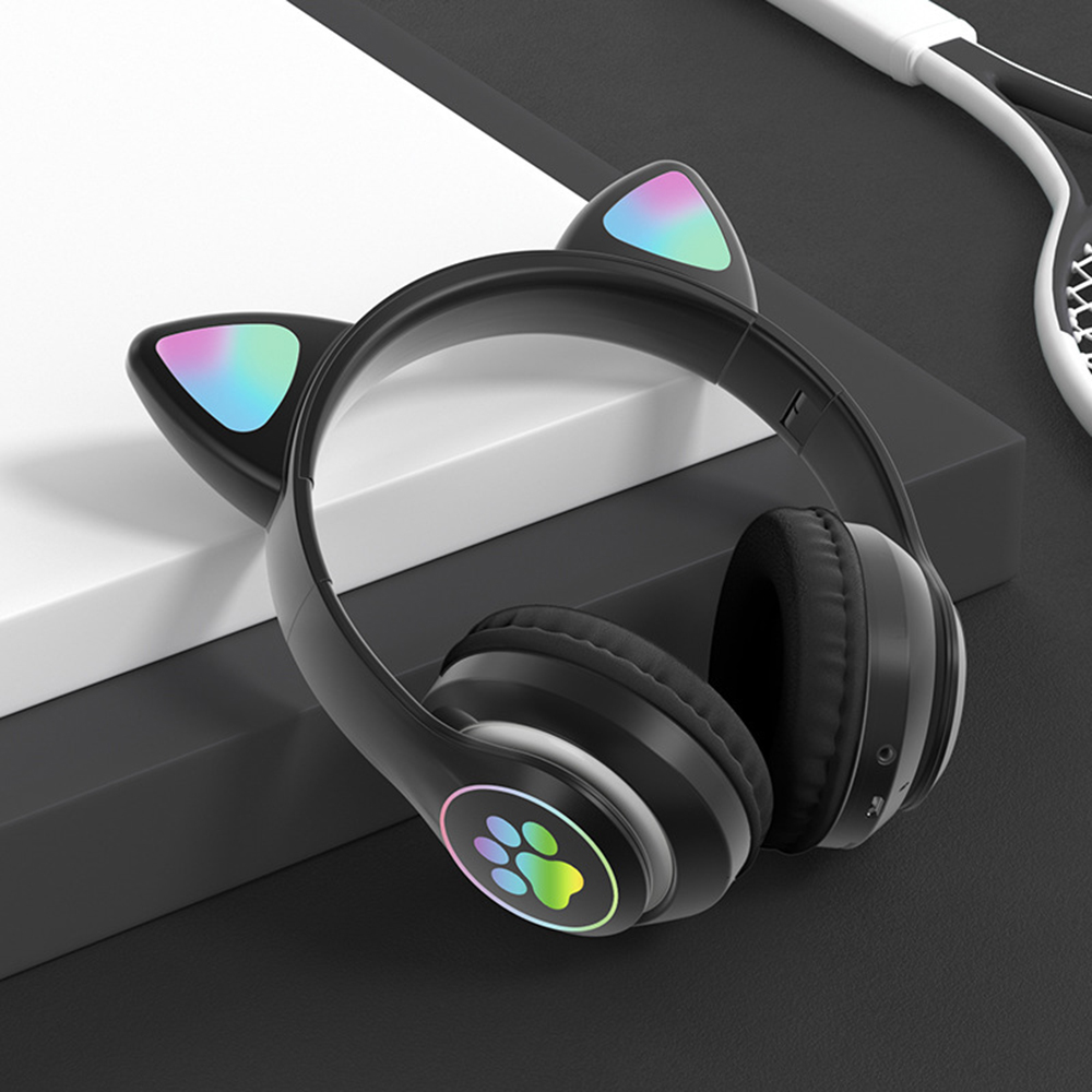 Schwarze Katzenohr-Kopfhörer mit regenbogenfarbenen Ohrendetails auf weißer Oberfläche.