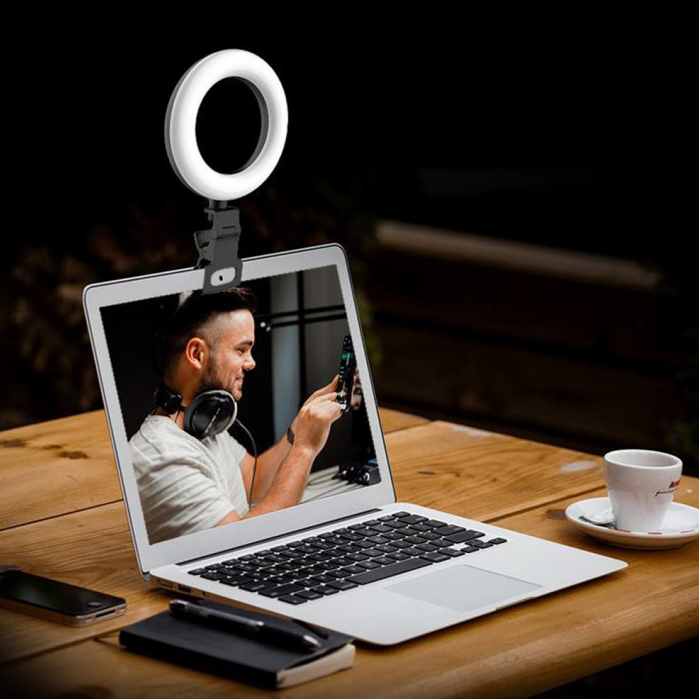 Laptop mit Ringlicht. Ein Mann ist auf dem Bildschirm, auf einem Holztisch.