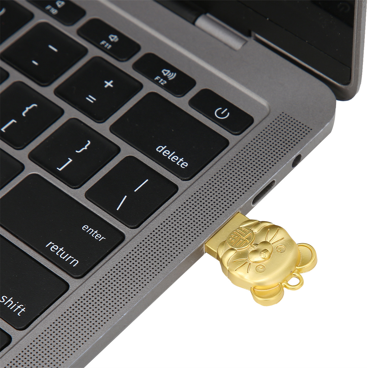 Ein goldener USB-Stick, der in einen Laptop gesteckt ist. Der Stick ist wie ein Bär mit chinesischen Schriftzeichen geformt.