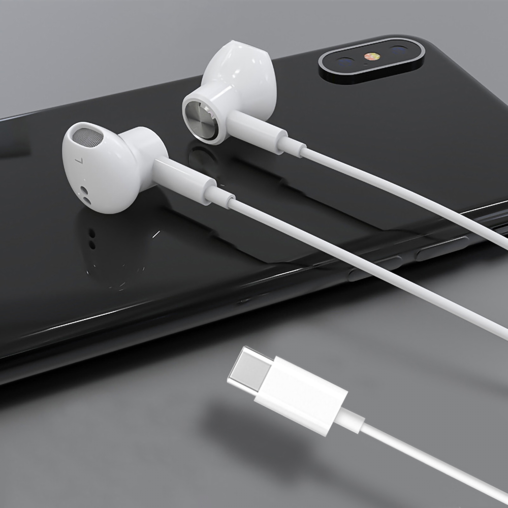 Weiße Ohrhörer mit Ladekabel liegen auf einem dunklen Telefon.