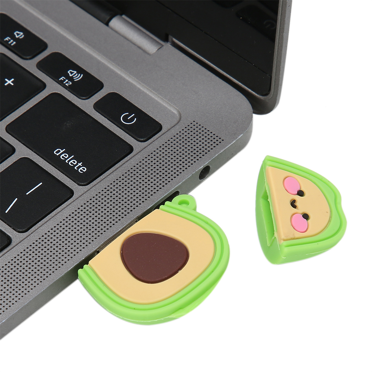 Zwei avocadoförmige USB-Sticks neben einem Laptop. Einer steckt im Laptop.
