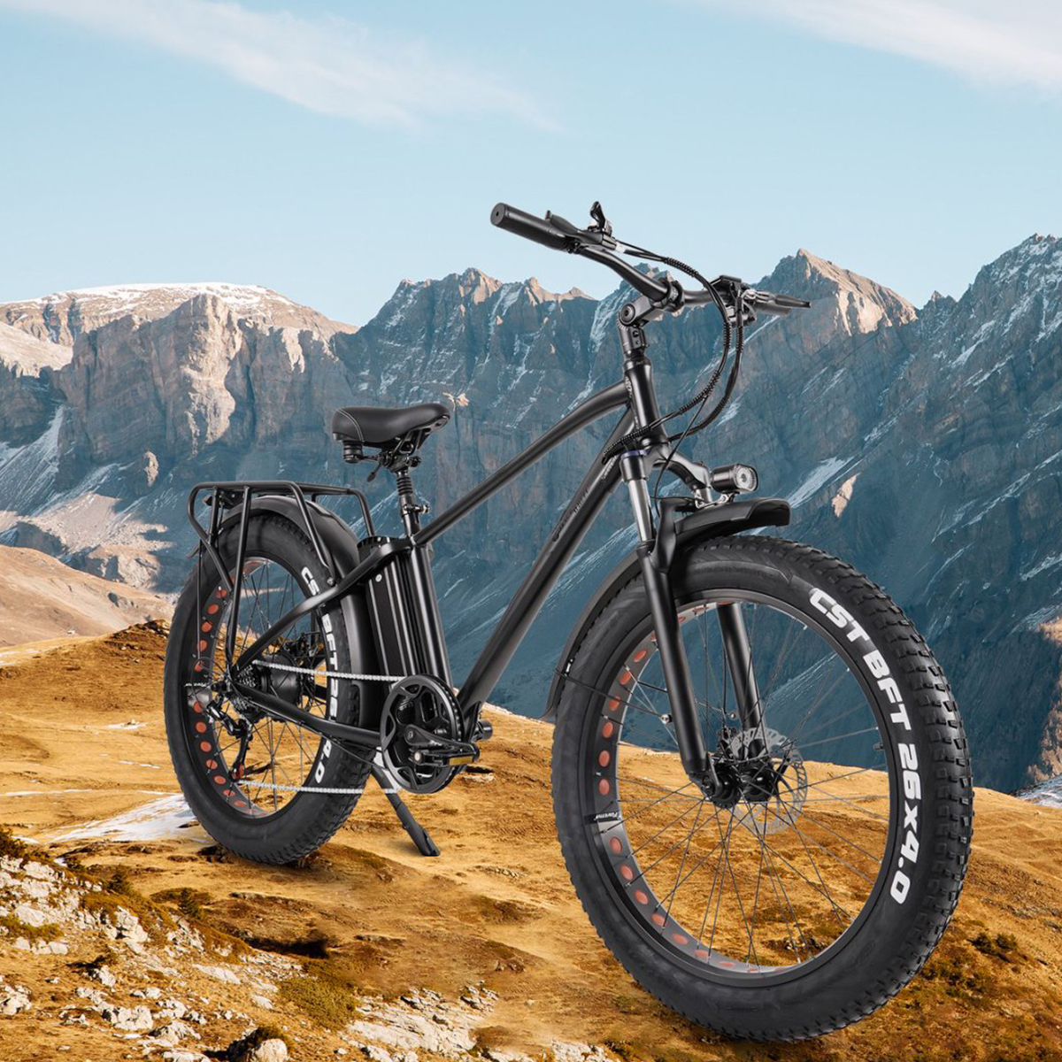 Czarny elektryczny rower z grubymi oponami na górskim szlaku z górami w tle.
