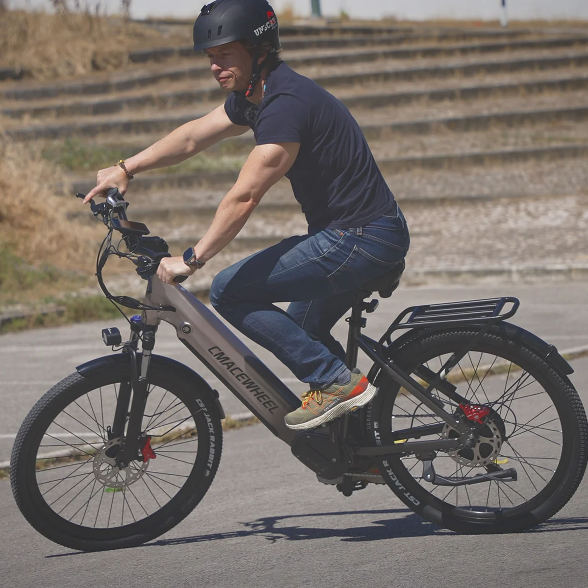 Czarny wentylator z okrągłą klatką i żółtym światłem pośrodku, na białym tle.