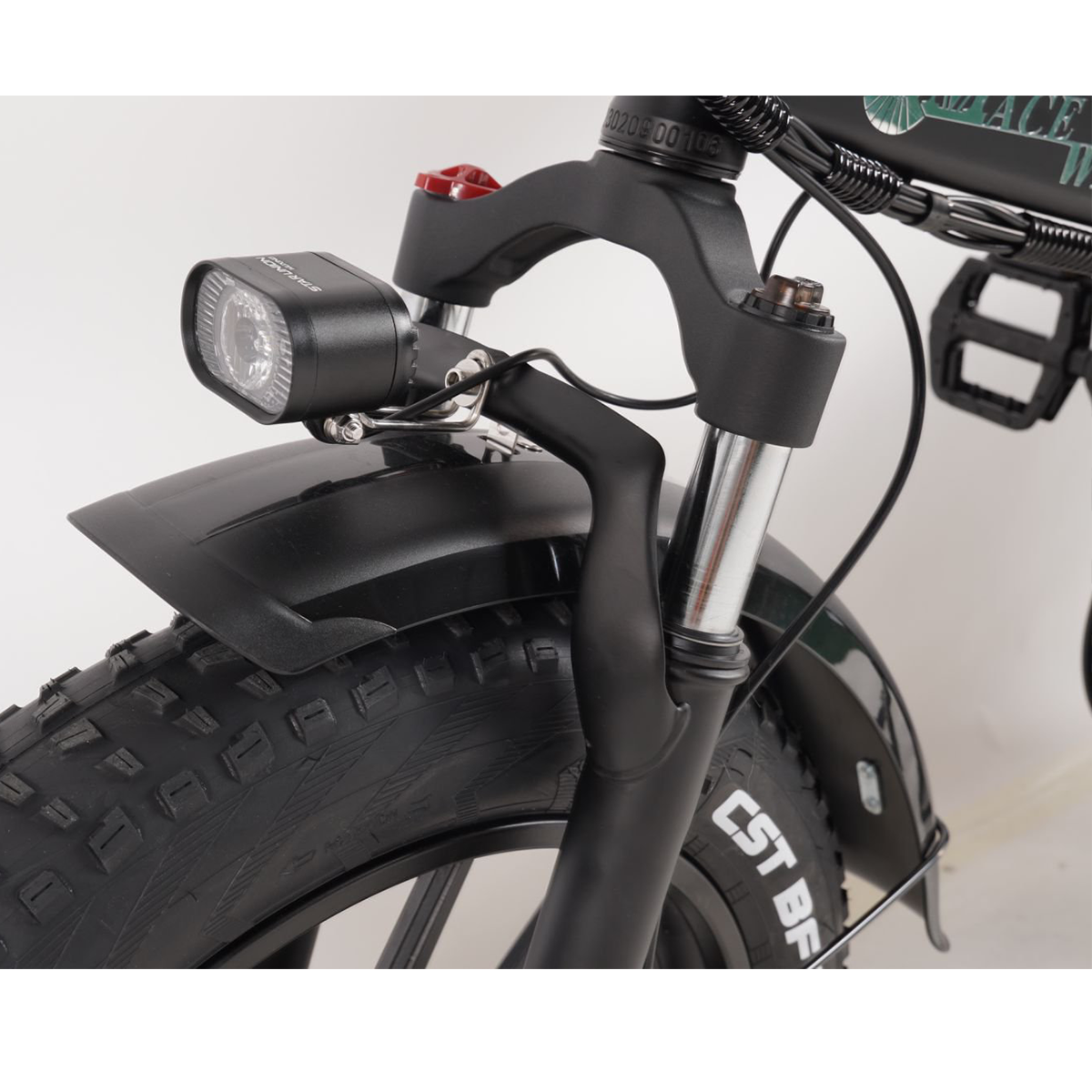 Zbliżenie czarnego elektrycznego roweru z grubymi oponami, pokazujące przednie koło, światło i zawieszenie.