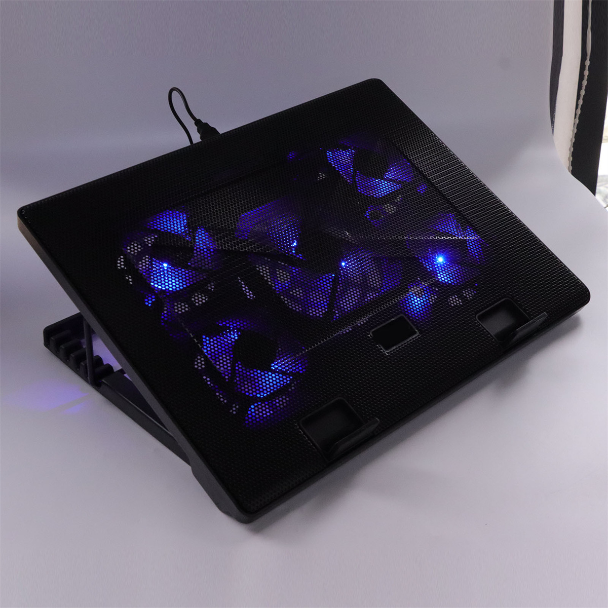 Ein schwarzes Laptop-Kühlpad mit blauen LED-Leuchten, die die Mesh-Oberfläche beleuchten.