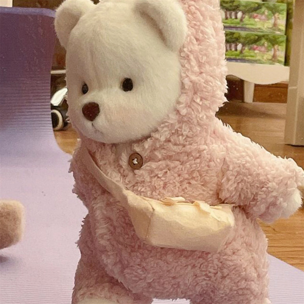 Rosa Teddybär mit rosa Kapuzenpulli und kleiner beiger Tasche.