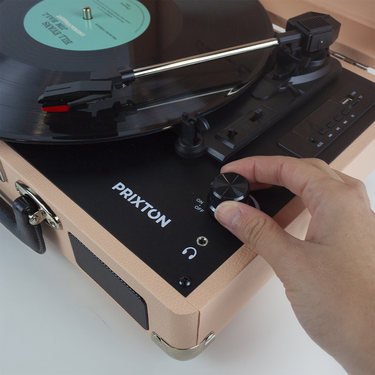 Zbliżenie gramofonu, z ręką regulującą pokrętło głośności.