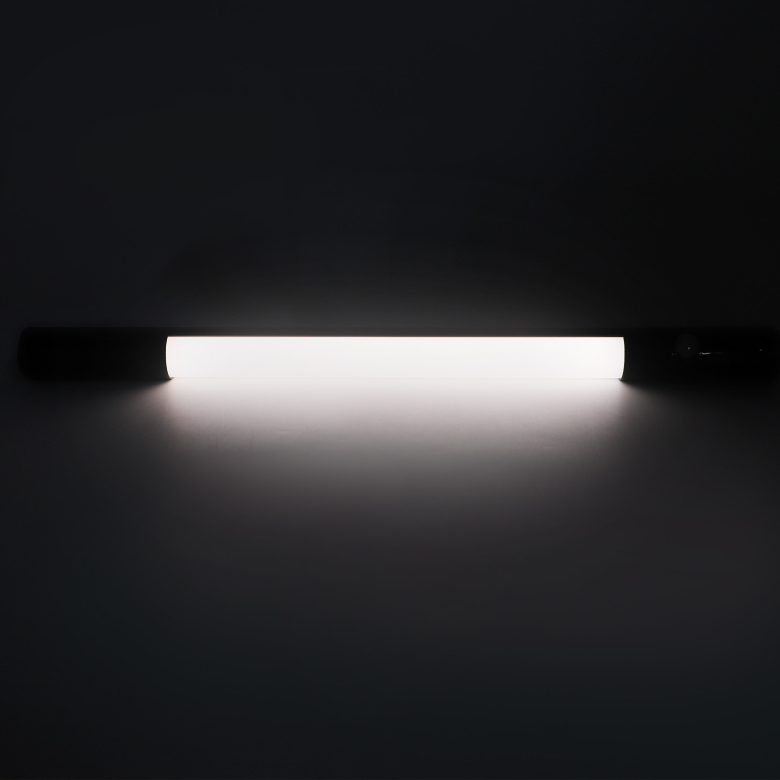 Ein langer, weißer Lichtbalken mit schwarzen Enden auf dunklem Hintergrund.
