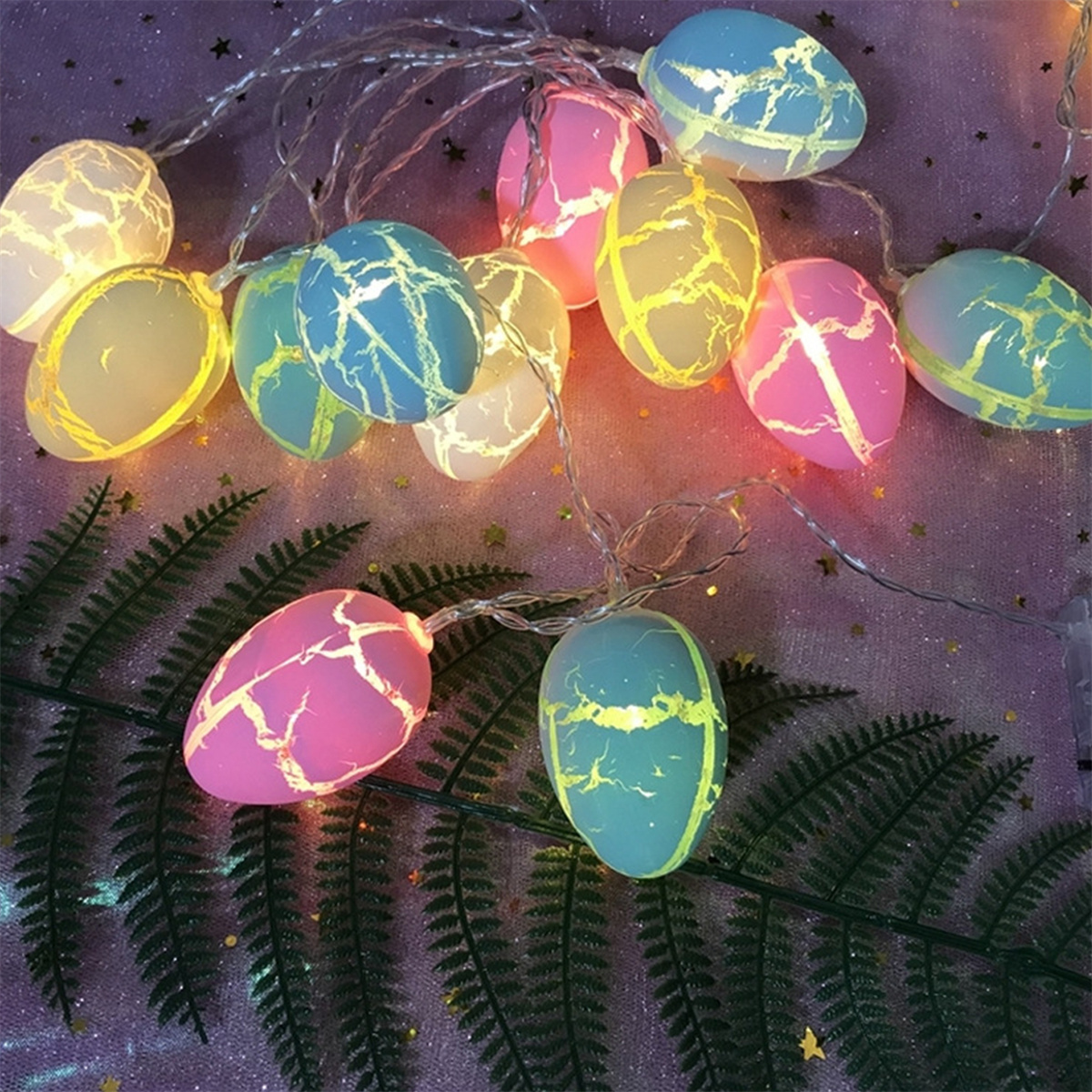 Ostereier-Lichter. Mehrere beleuchtete bunte Eier auf einer lila Oberfläche. Die Eier haben Muster.