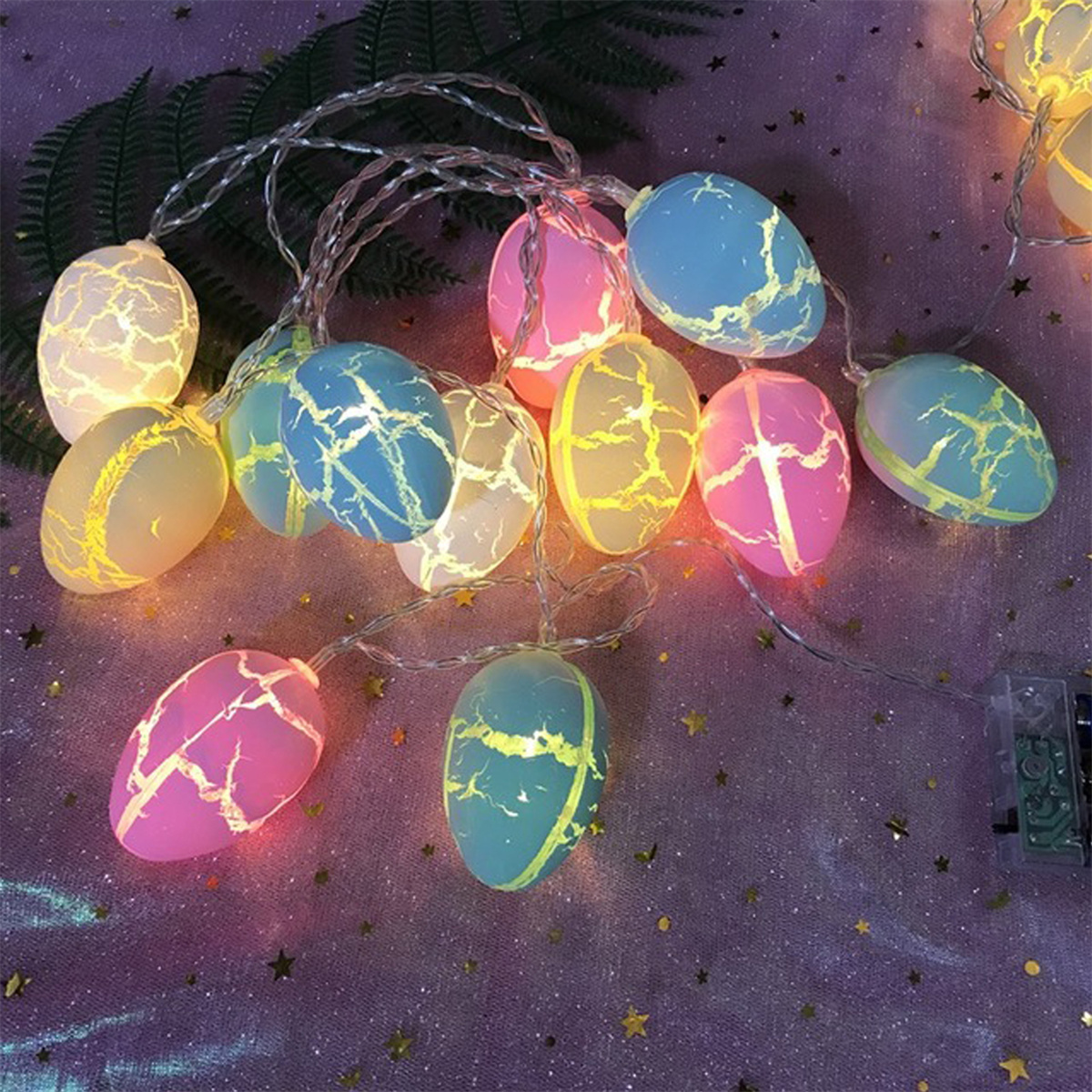 Eine Lichterkette mit bunten, eiförmigen Lichtern. Sie sind beleuchtet und auf dunklem Hintergrund.