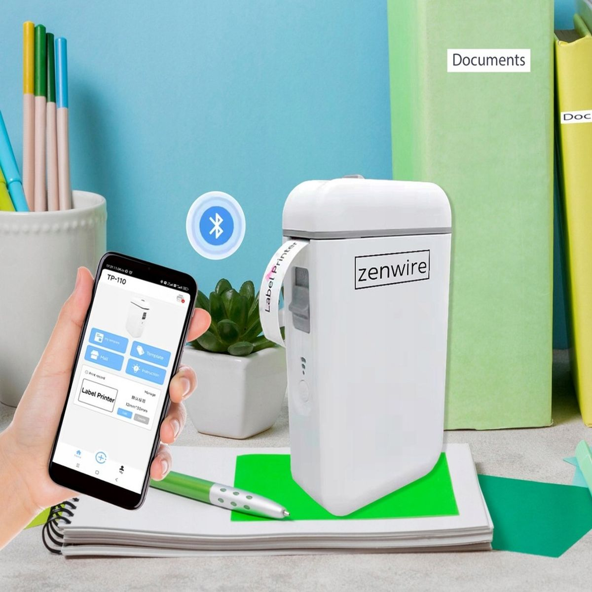 Biała drukarka etykiet z telefonem, długopisem i książkami w tle.