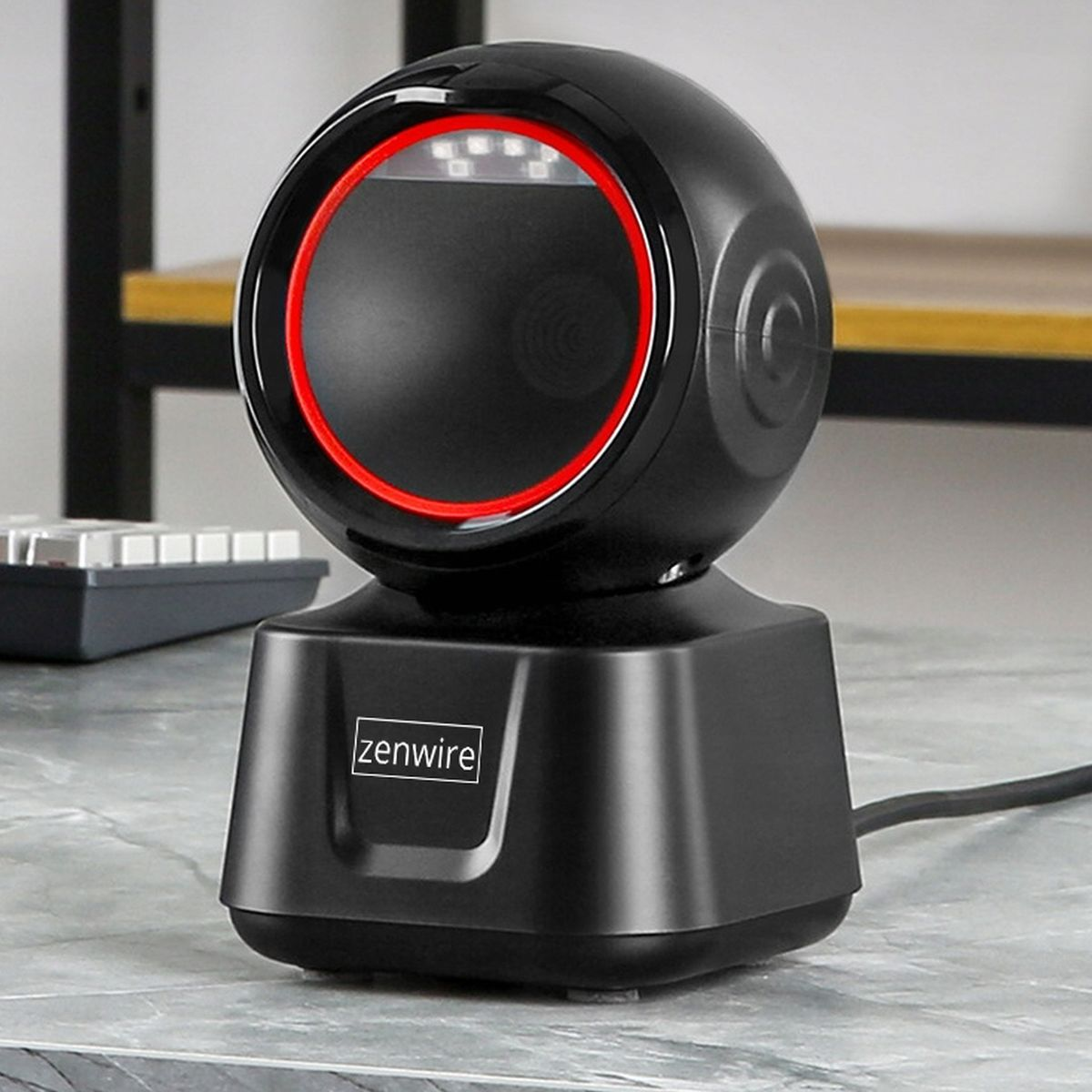 Czarny skaner kodów kreskowych z czerwonym pierścieniem światła, na marmurowej powierzchni.