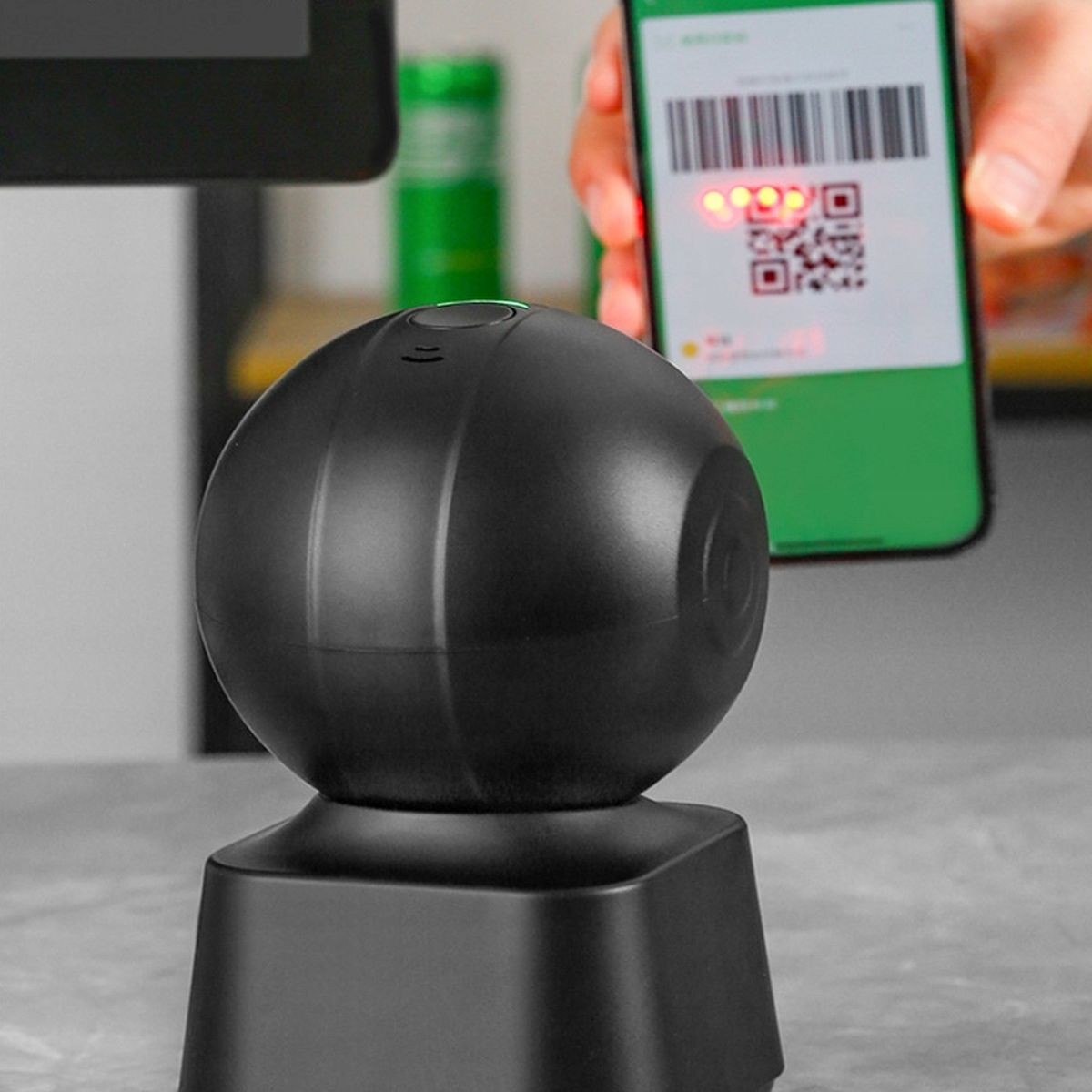 Czarny skaner kulisty na podstawie obok telefonu z kodem QR.