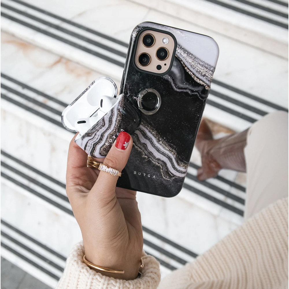 Een vrouw die een telefoon vasthoudt met een marmeren hoesje en een Airpods-hoesje. Ring en armband zijn zichtbaar.