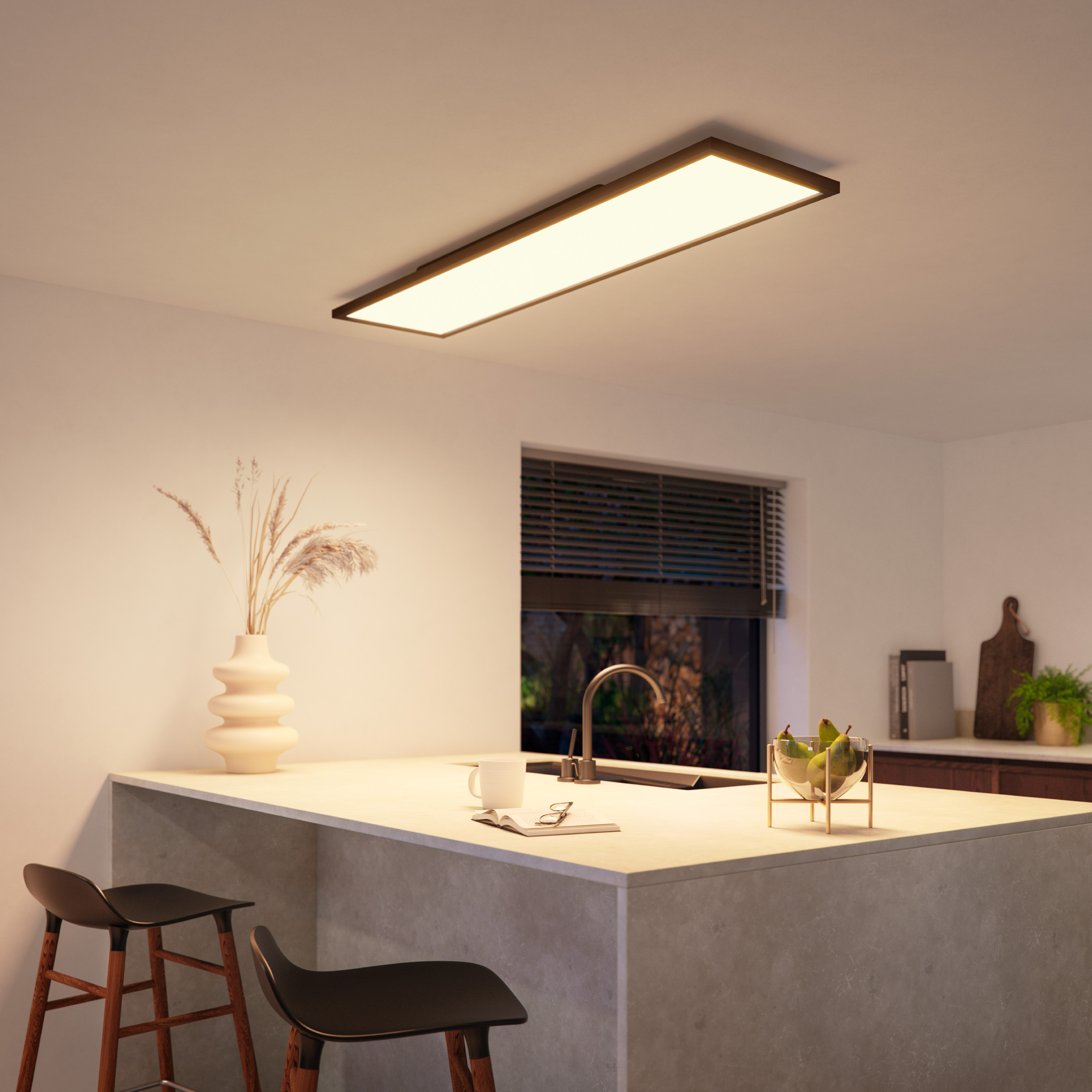 Una cucina con una luce a soffitto rettangolare, un lavandino e un bancone con sgabelli.