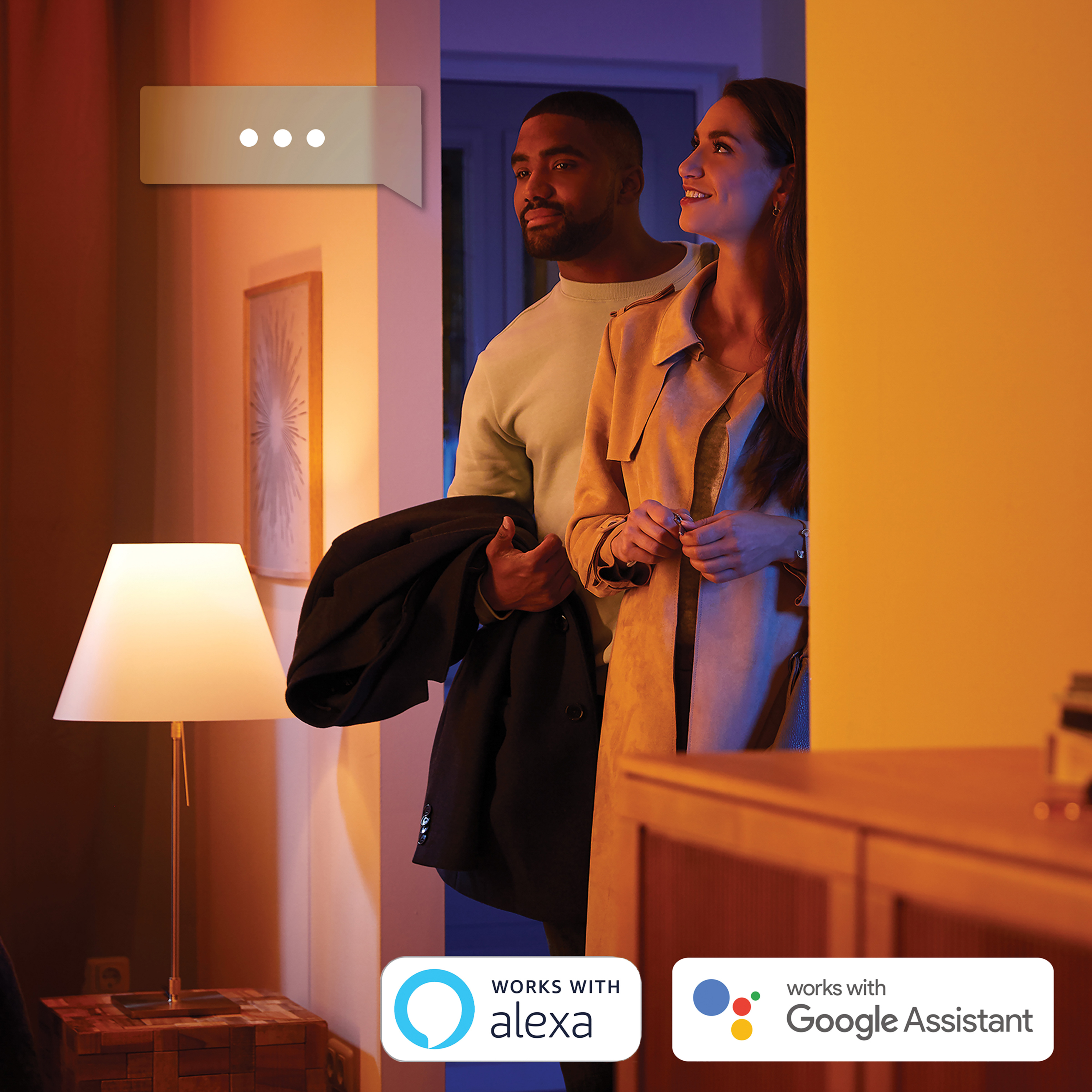 Coppia in una stanza, che guarda verso una porta. Una lampada è accesa. I testi dicono: "Funziona con Alexa" e "Google Assistant".