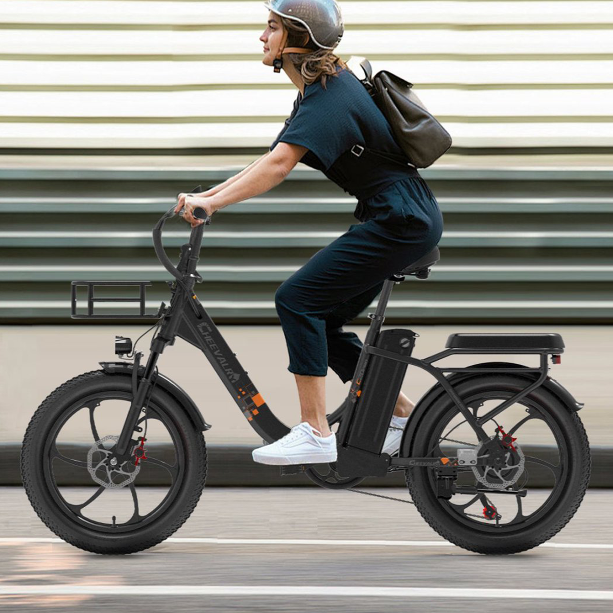 Osoba jadąca czarnym rowerem elektrycznym na ulicy, w kasku i z plecakiem.