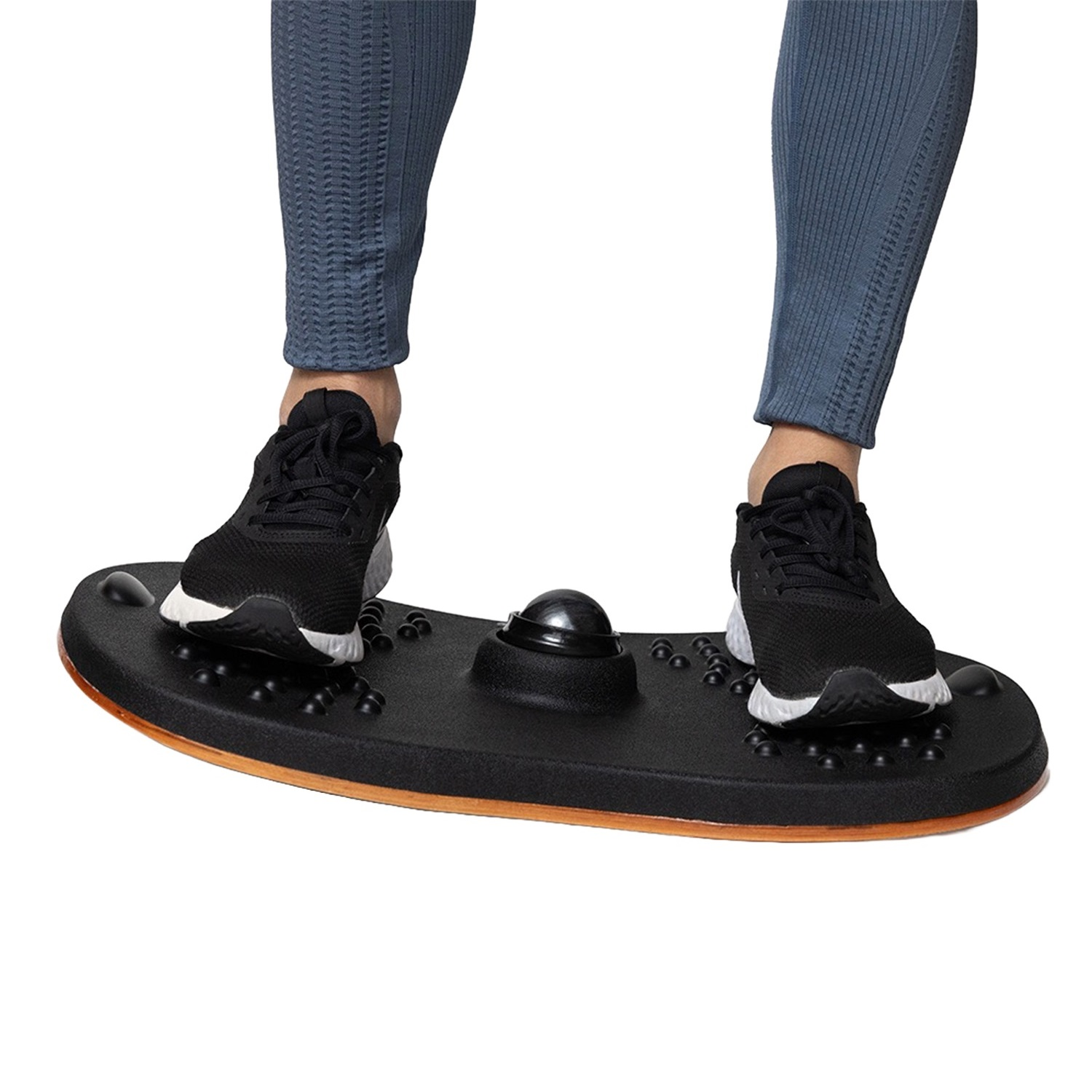 Füße einer Person auf einem schwarzen Balance Board mit Kugel und Noppen.