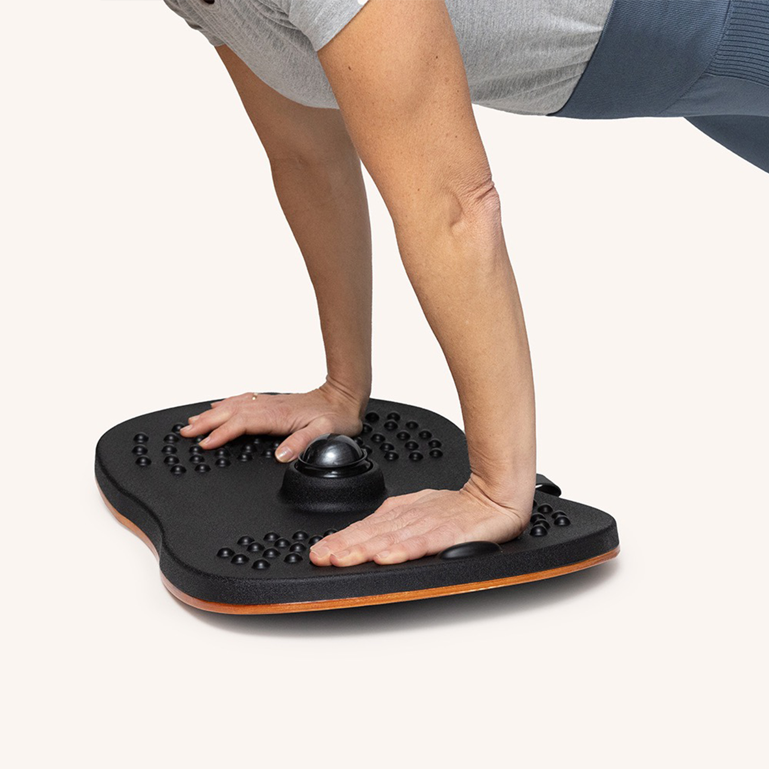 Eine Person macht Liegestütze auf einem schwarzen Balance Board. Das Board hat schwarze Knöpfe und einen orangen Rand.
