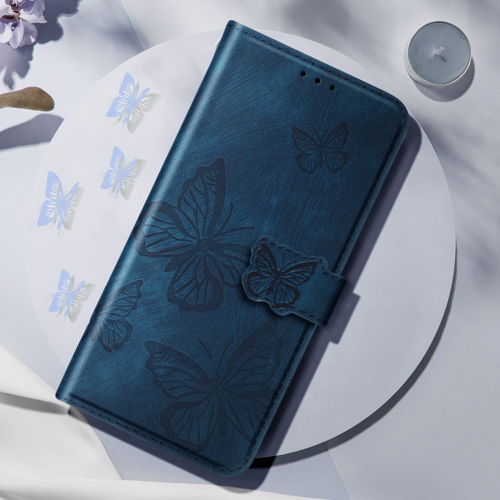 Blaue Handyhülle mit Schmetterlingsdesign. Die Hülle ist offen, mit weißer Oberfläche.