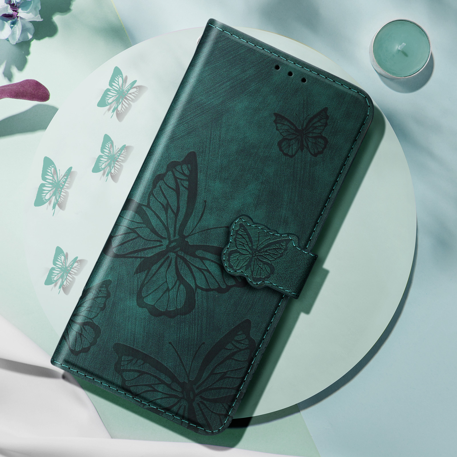 Custodia per telefono verde scuro con motivi a farfalla su superficie verde chiaro.