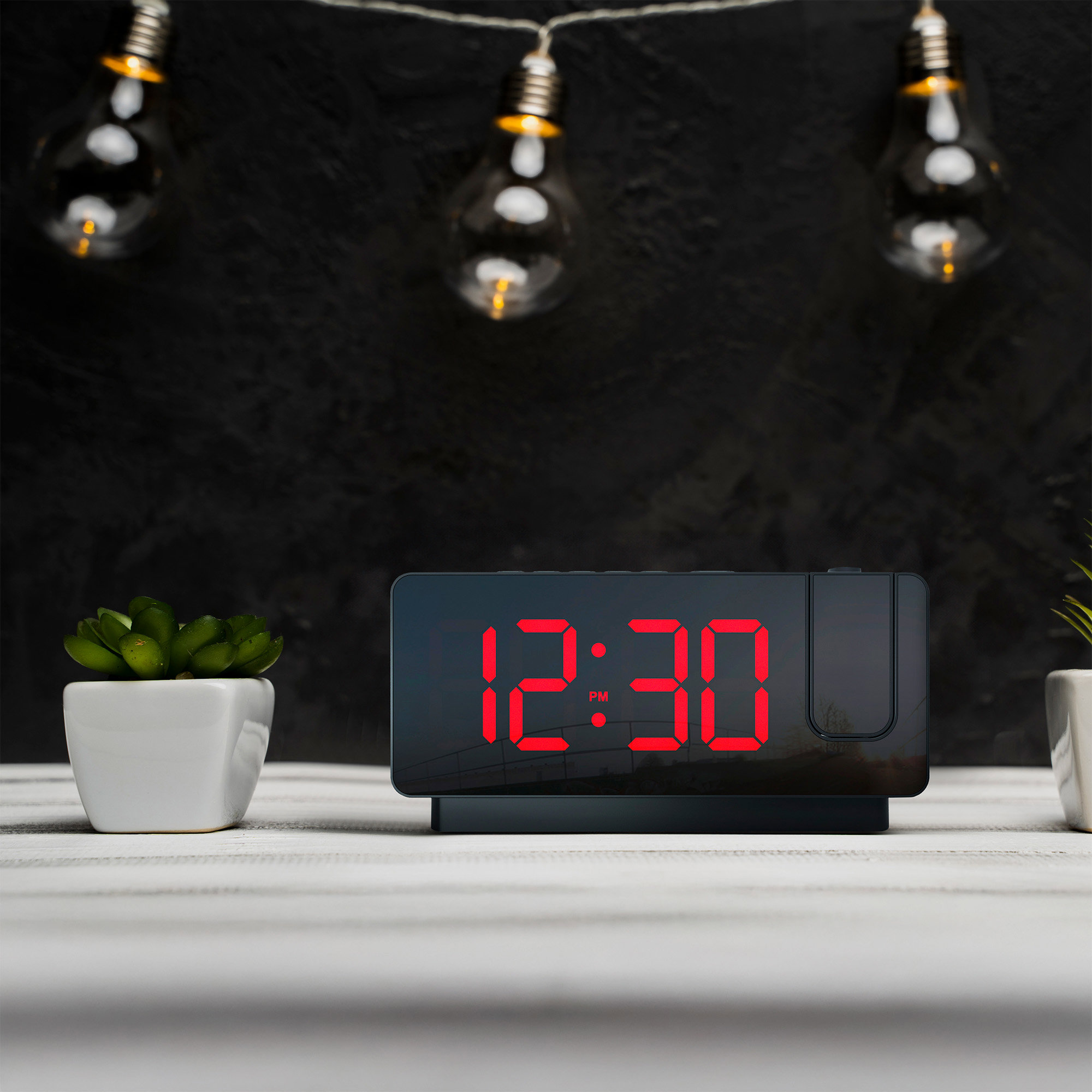 Digital clock projecting red numbers onto a wall, with plants and lights.