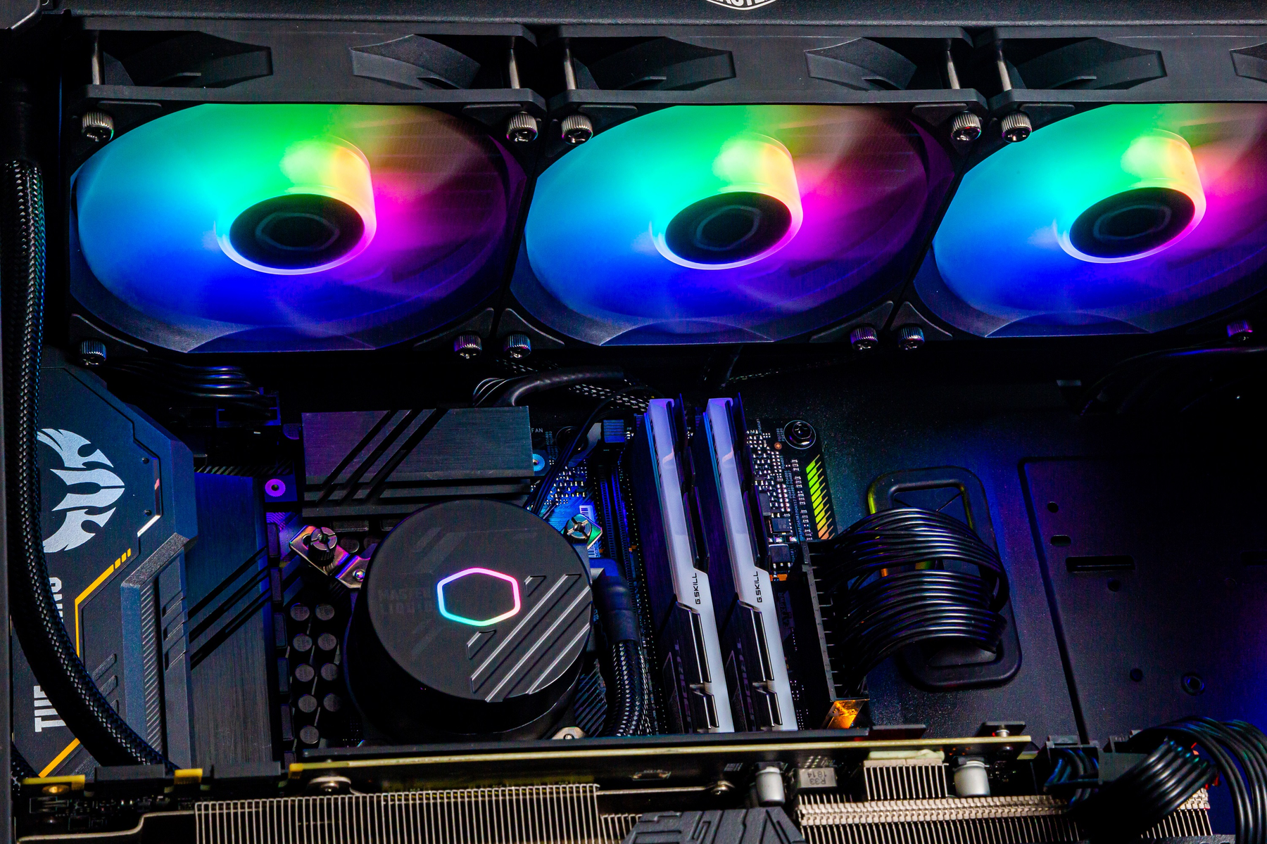 Wnętrze komputera z trzema wielokolorowymi wentylatorami, chłodzeniem i różnymi komponentami.
