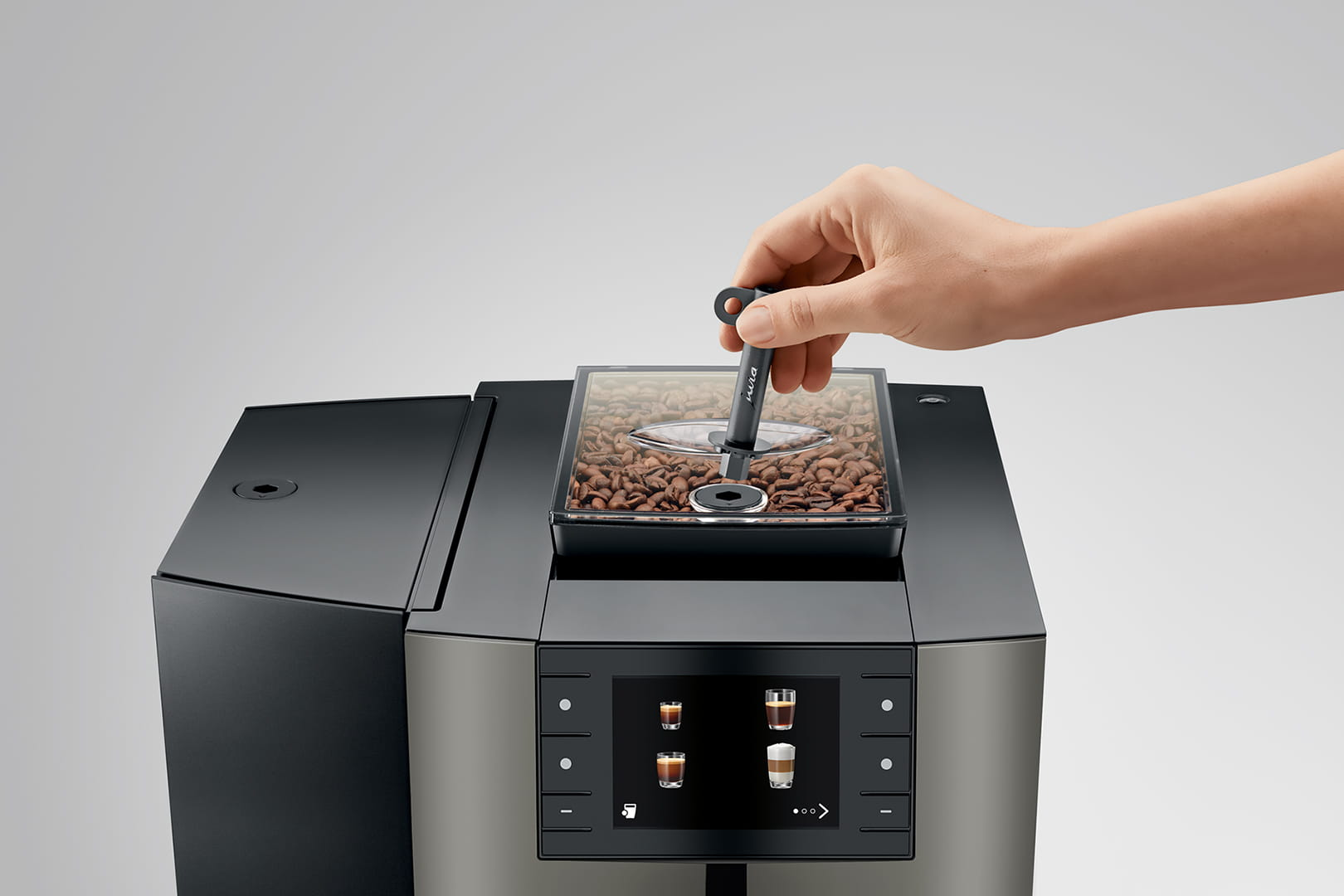 Die Hand einer Person fügt Kaffeebohnen in eine Kaffeemaschine ein.