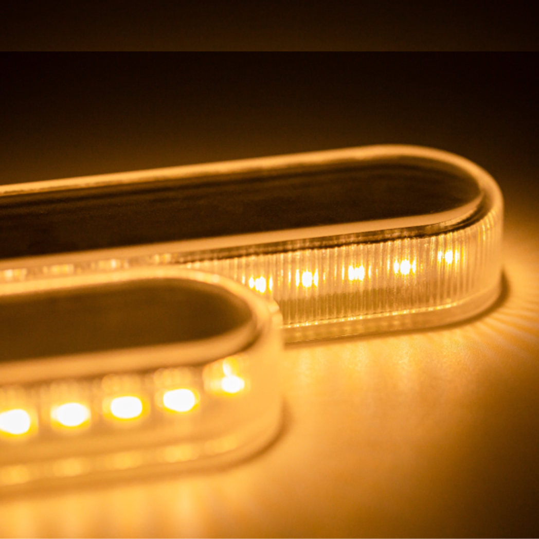 Zwei beleuchtete, längliche LED-Leuchten, gelbes Leuchten, nebeneinander, auf dunkler Oberfläche.