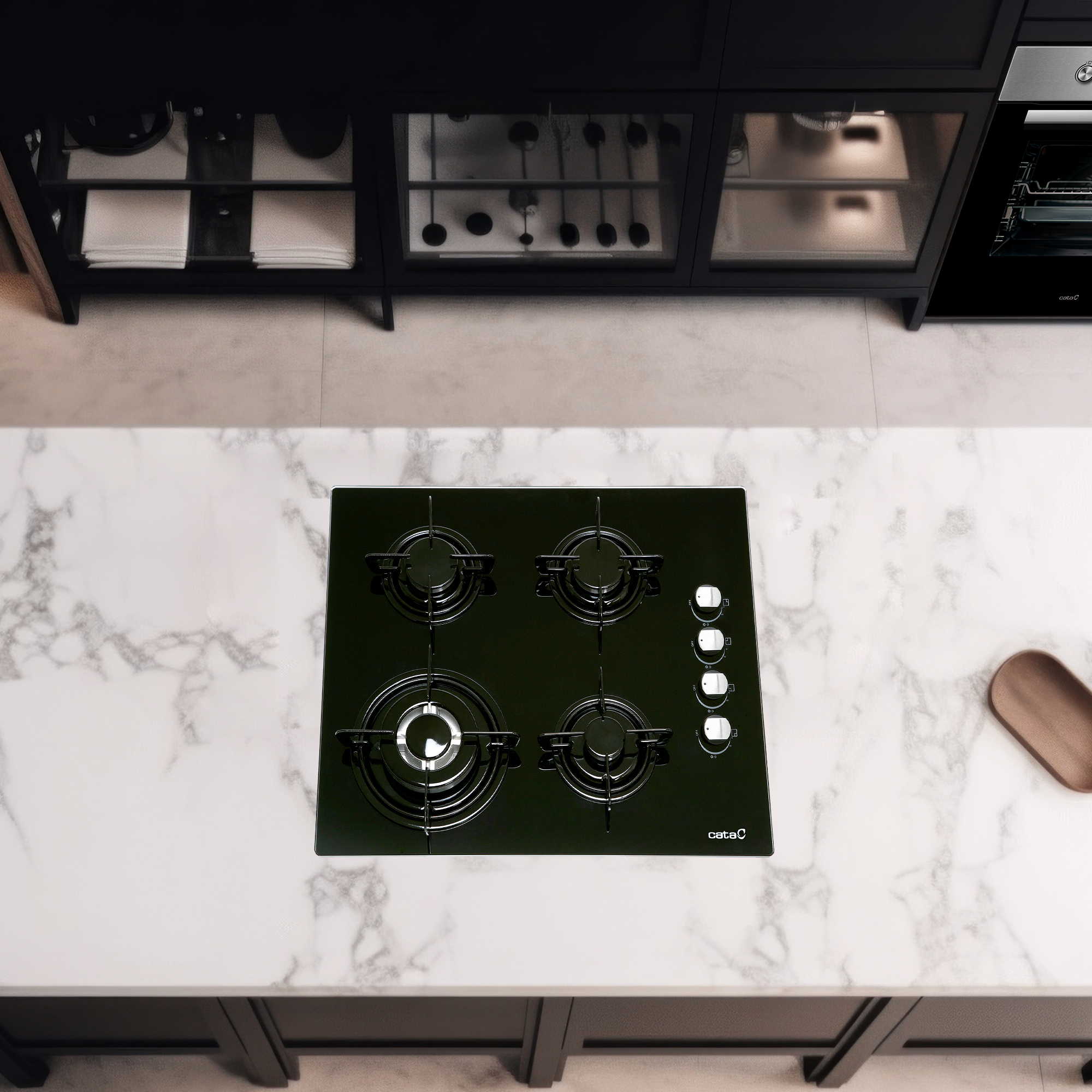 Widok z góry na czarną płytę kuchenną z czterema palnikami na marmurowym blacie.
