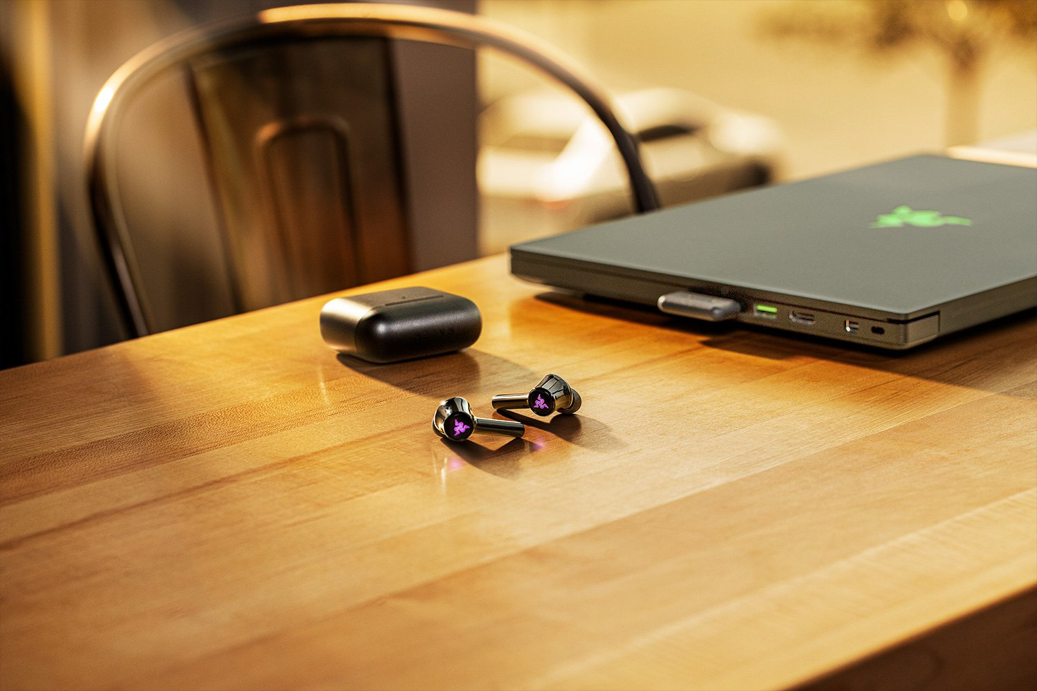 Auricolari wireless, laptop e custodia su tavolo legno.