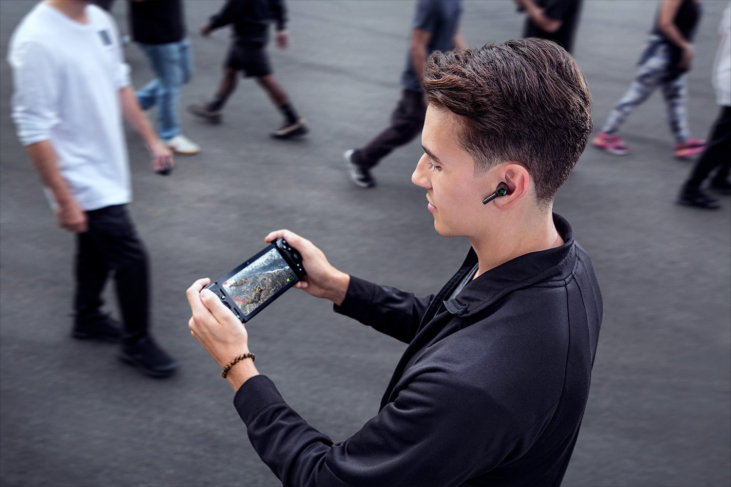 Uomo con telefono e auricolari. Persone sullo sfondo.