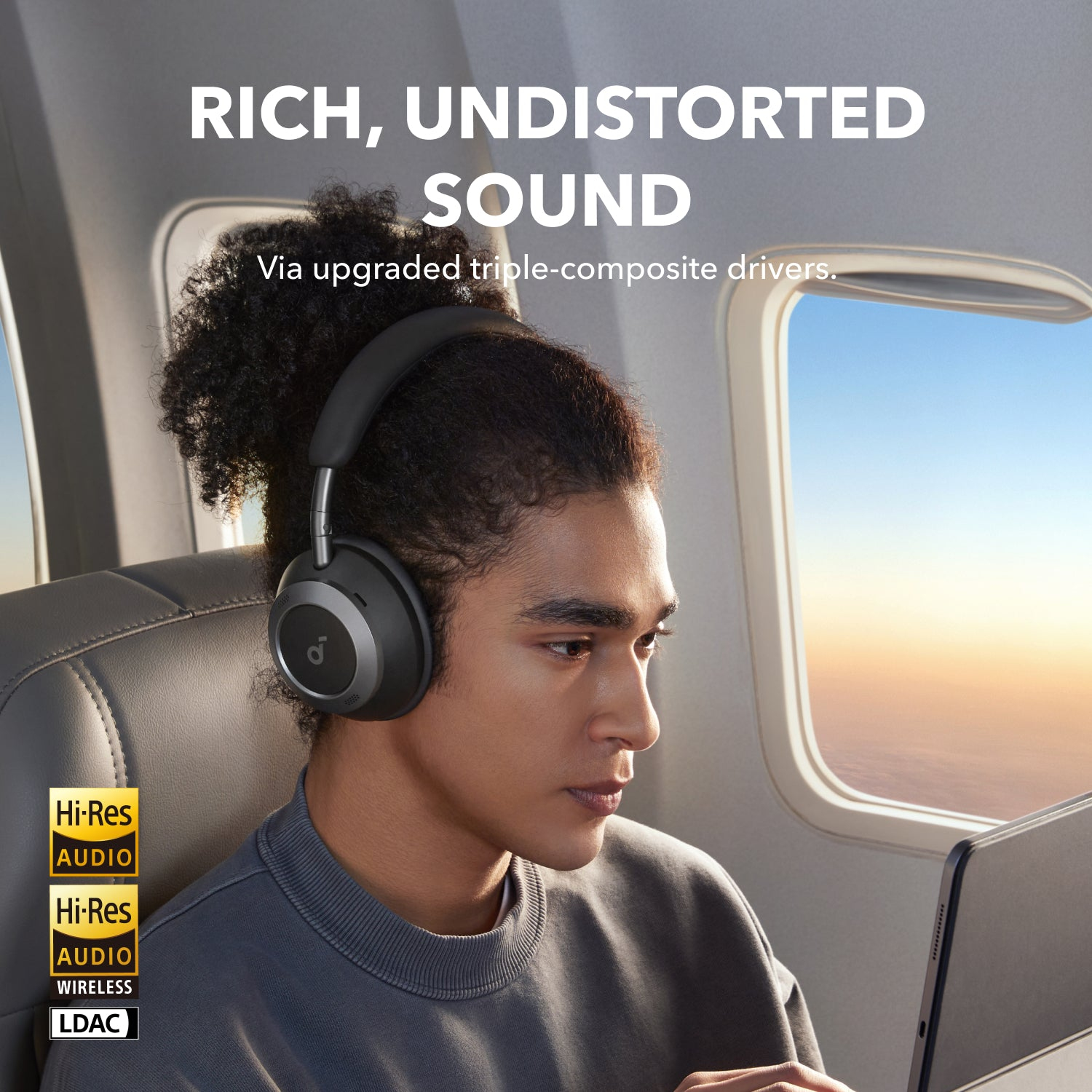 Mann trägt schwarze Kopfhörer, sitzt im Flugzeug, Text: 'Reicher, unverfälschter Sound'.