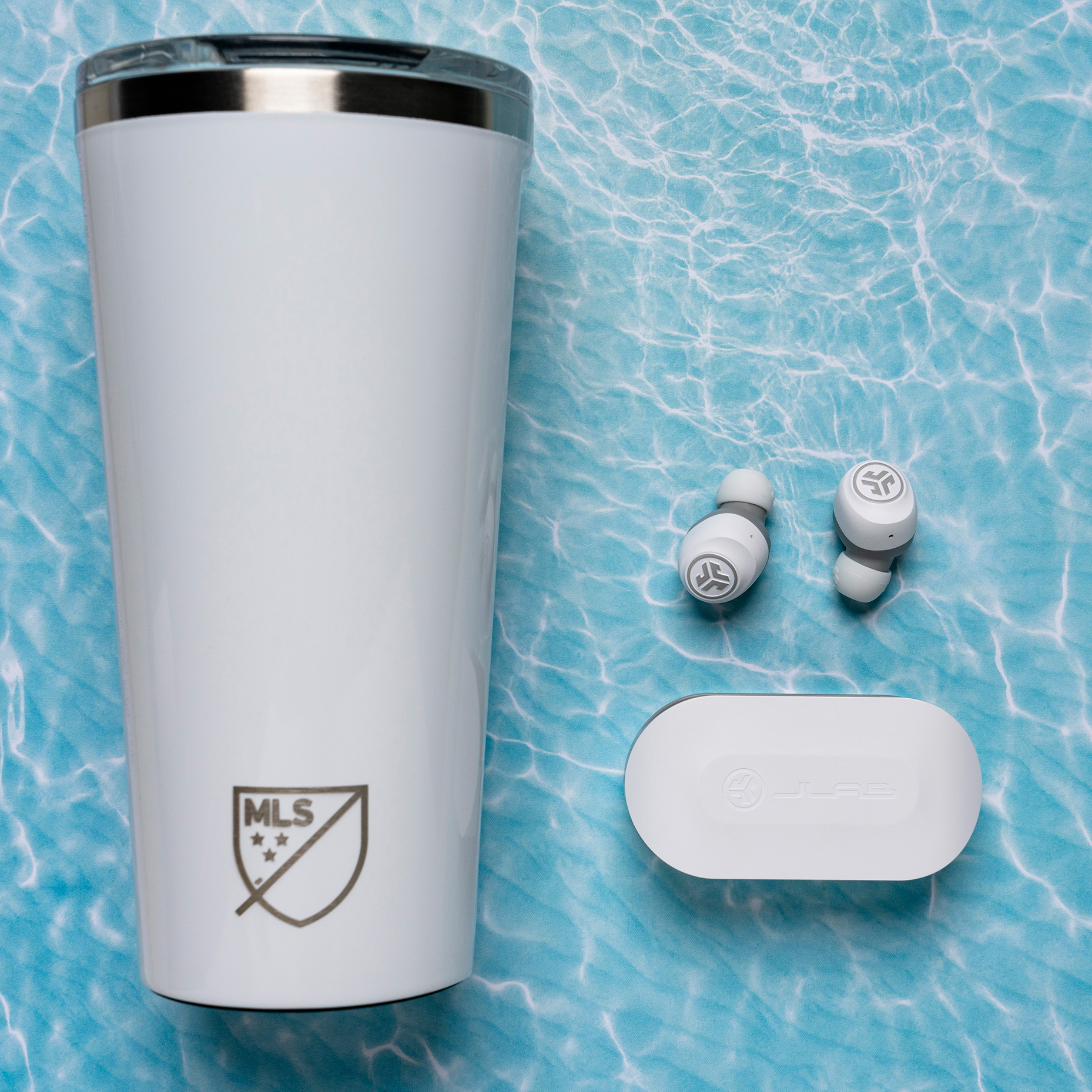 Vaso y auriculares blancos sobre una superficie azul con patrón de agua.