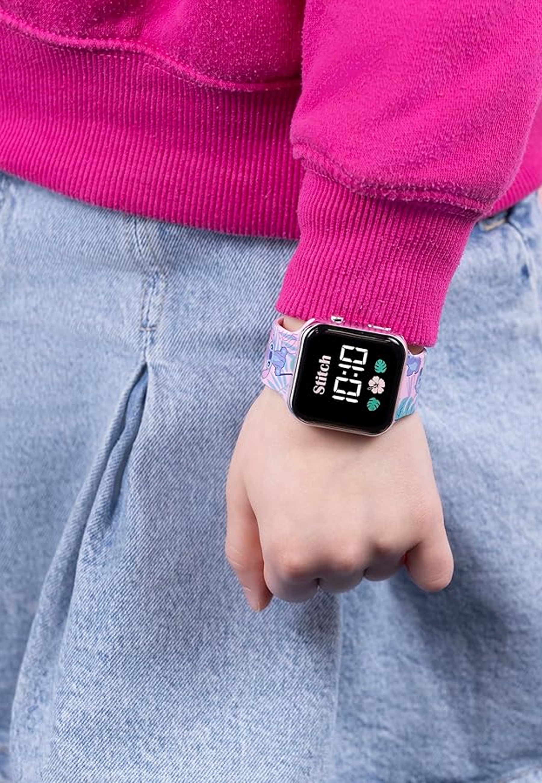 Le poignet d'une personne avec une montre numérique affichant l'heure sur un bracelet floral.