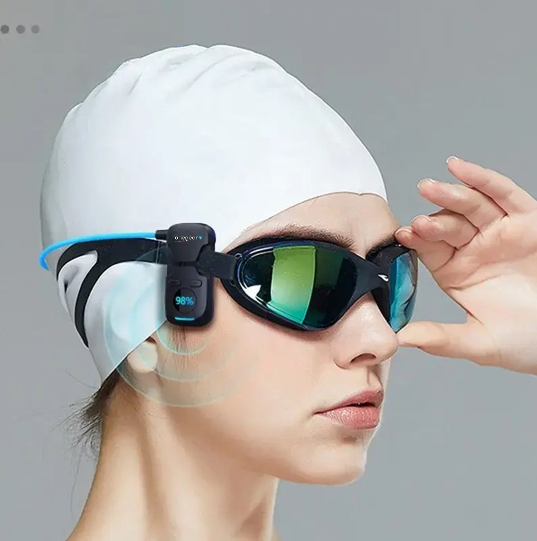 Donna con occhialini da nuoto e dispositivo. Una mano vicino al viso.