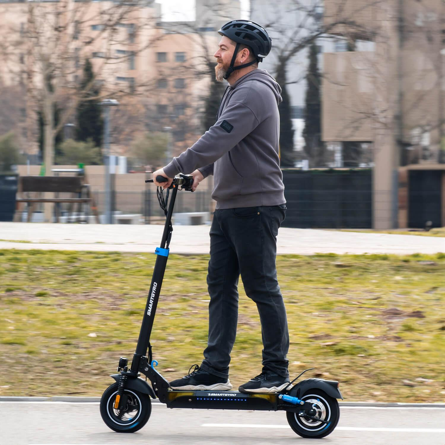 Mężczyzna na hulajnodze elektrycznej, w kasku, w parku. Słoneczny dzień.