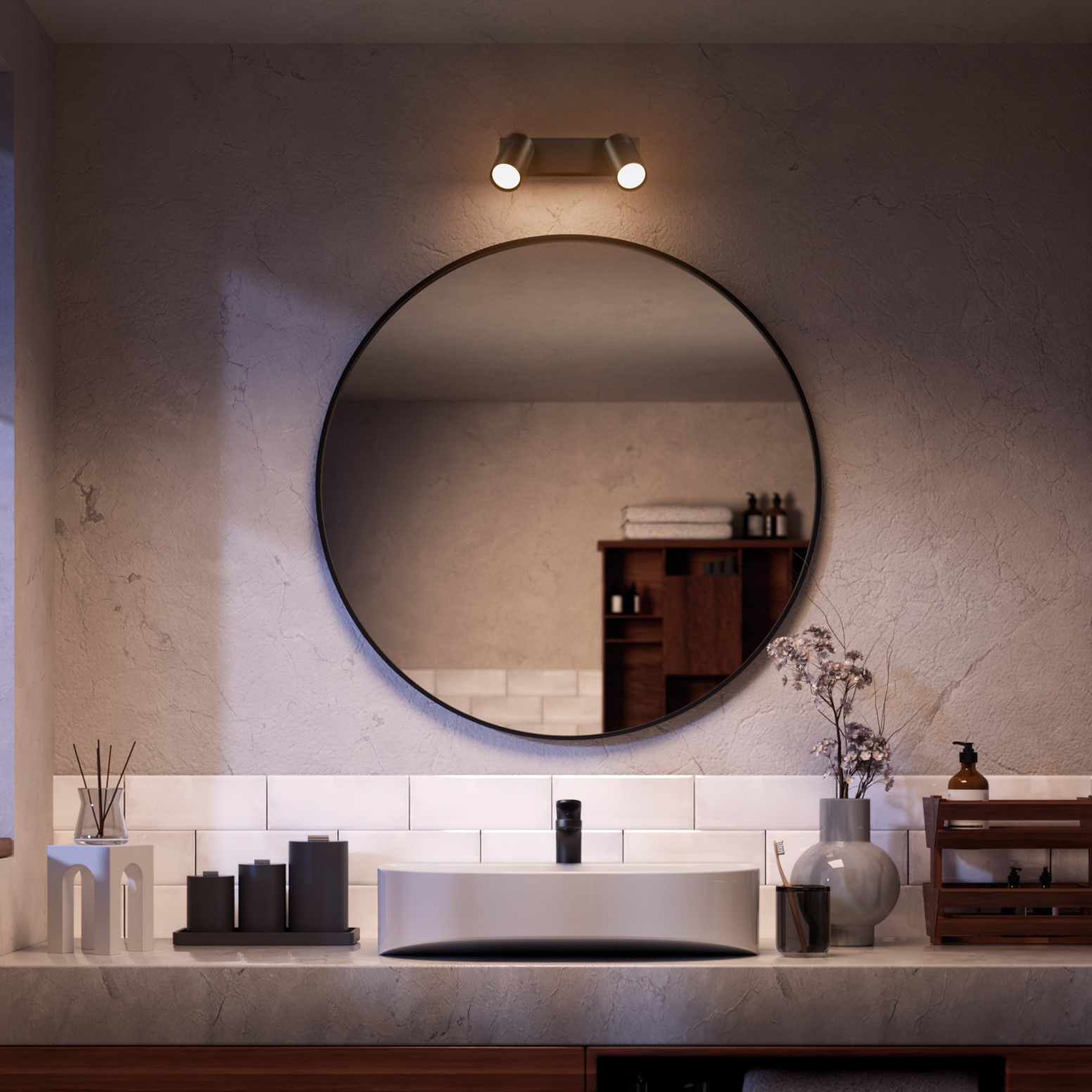 Bathroom with round mirror, sink, and two spotlights above.