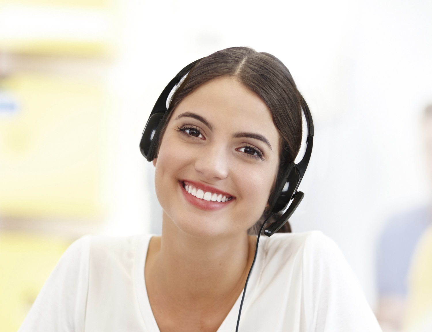 Una mujer con auriculares, sonriendo a la cámara. Tiene cabello oscuro.