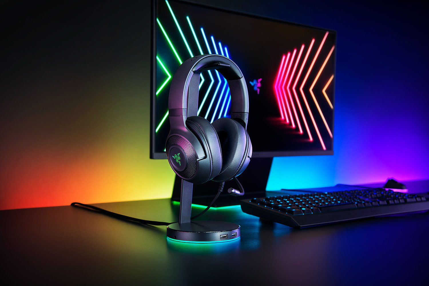 Cuffie nere su un supporto, poste su una scrivania davanti a uno schermo del computer.