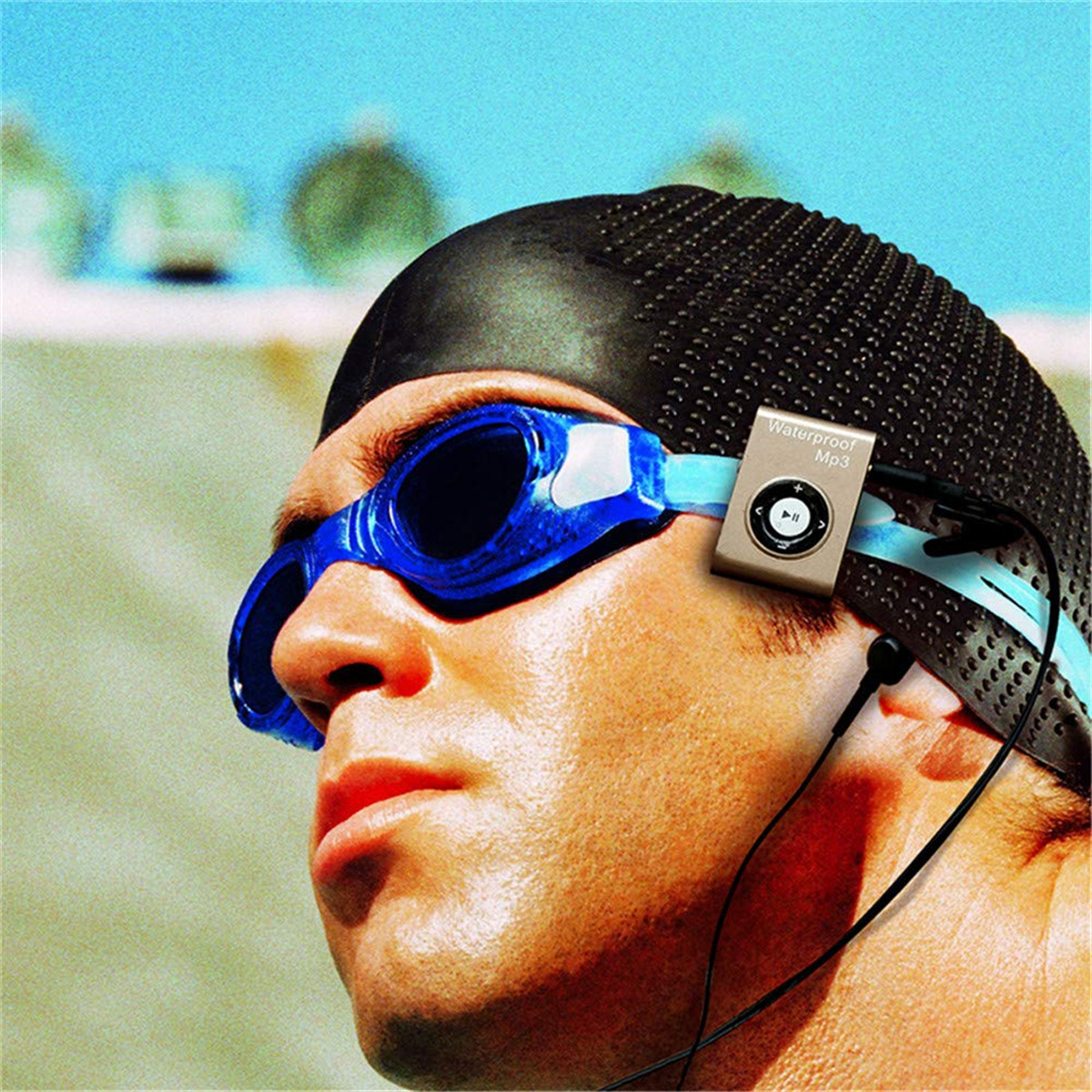 Mann mit Schwimmbrille und Mütze mit wasserdichtem MP3-Player. Blauer Wasserhintergrund.