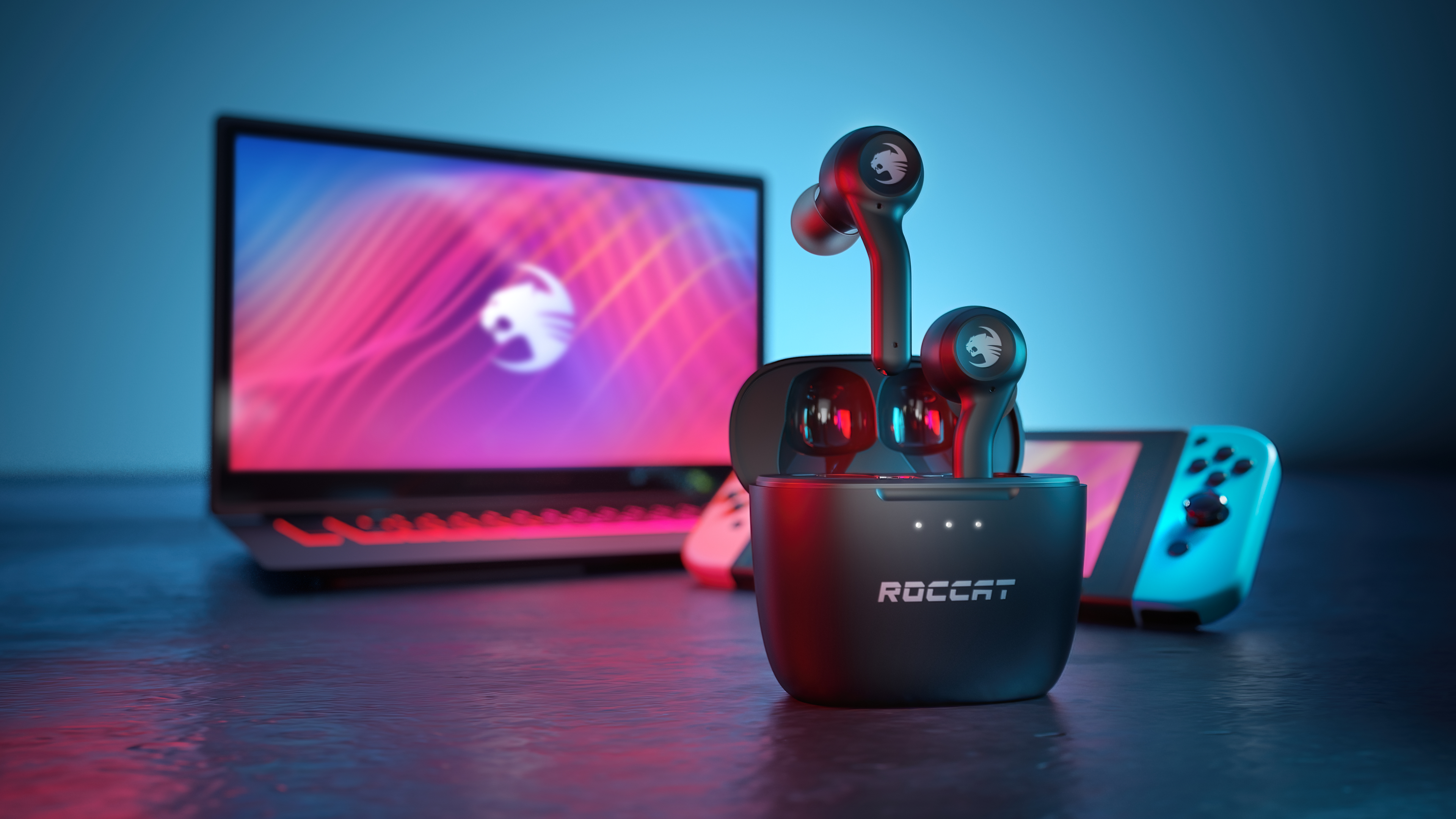 Auricolari in una custodia di ricarica. Un laptop e una Nintendo Switch sullo sfondo.