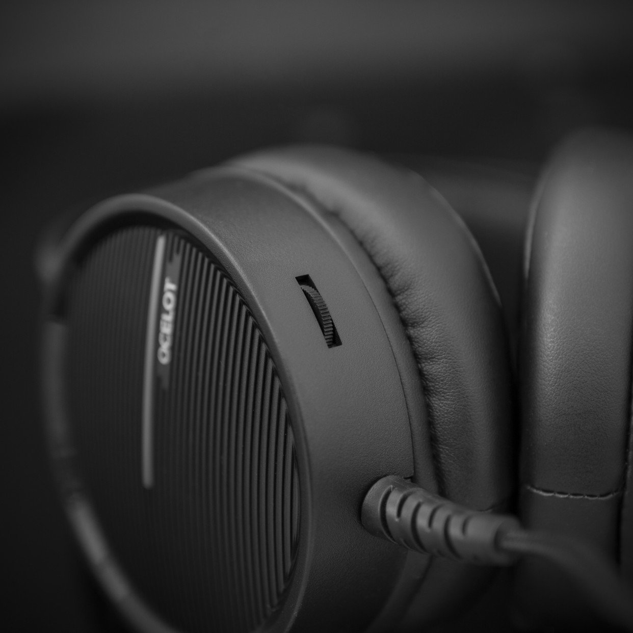 Czarne słuchawki, zbliżenie. Regulacja głośności jest widoczna. Ciemne tło.