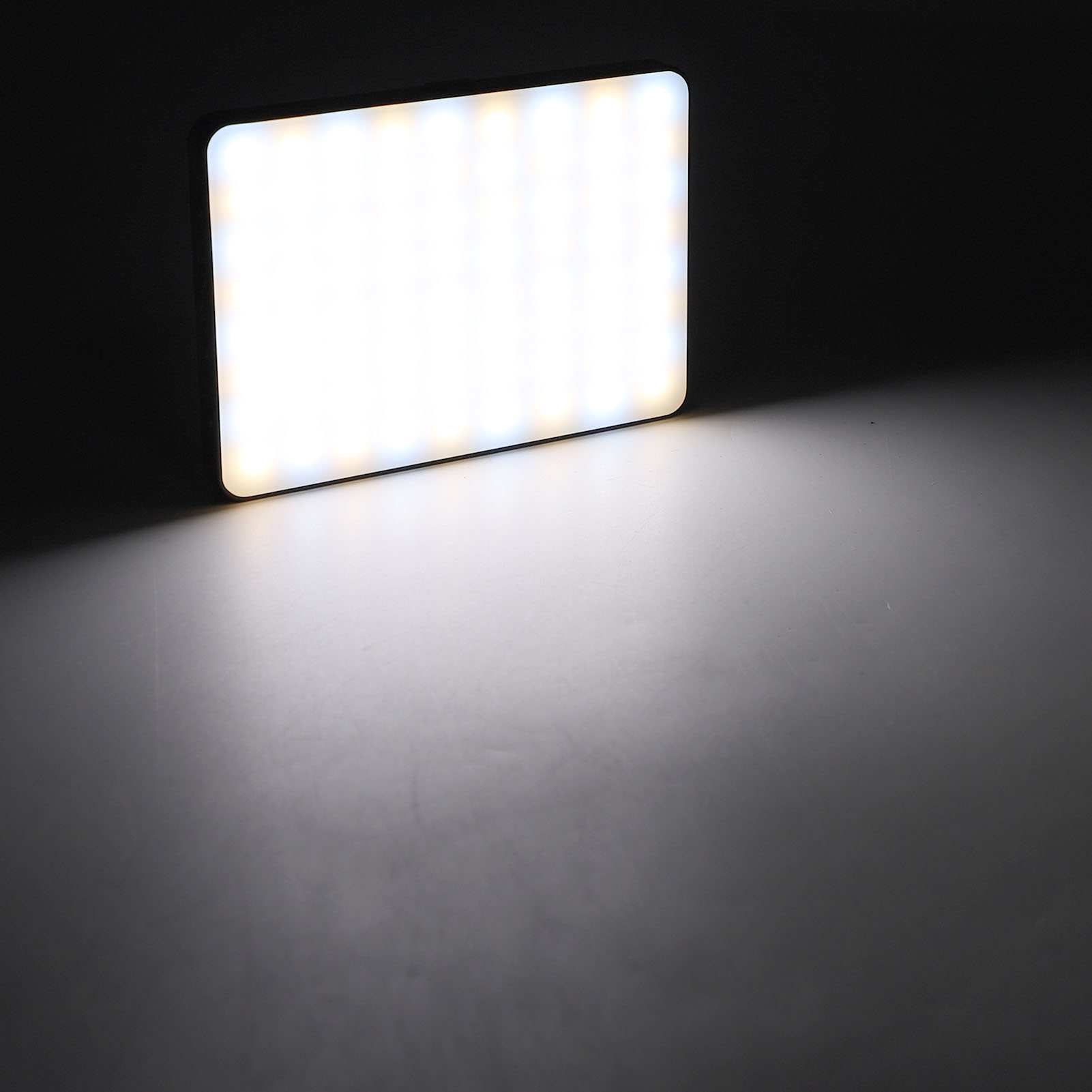 Ein helles, rechteckiges LED-Lichtpaneel auf dunkler Oberfläche. Das Licht scheint nach unten.
