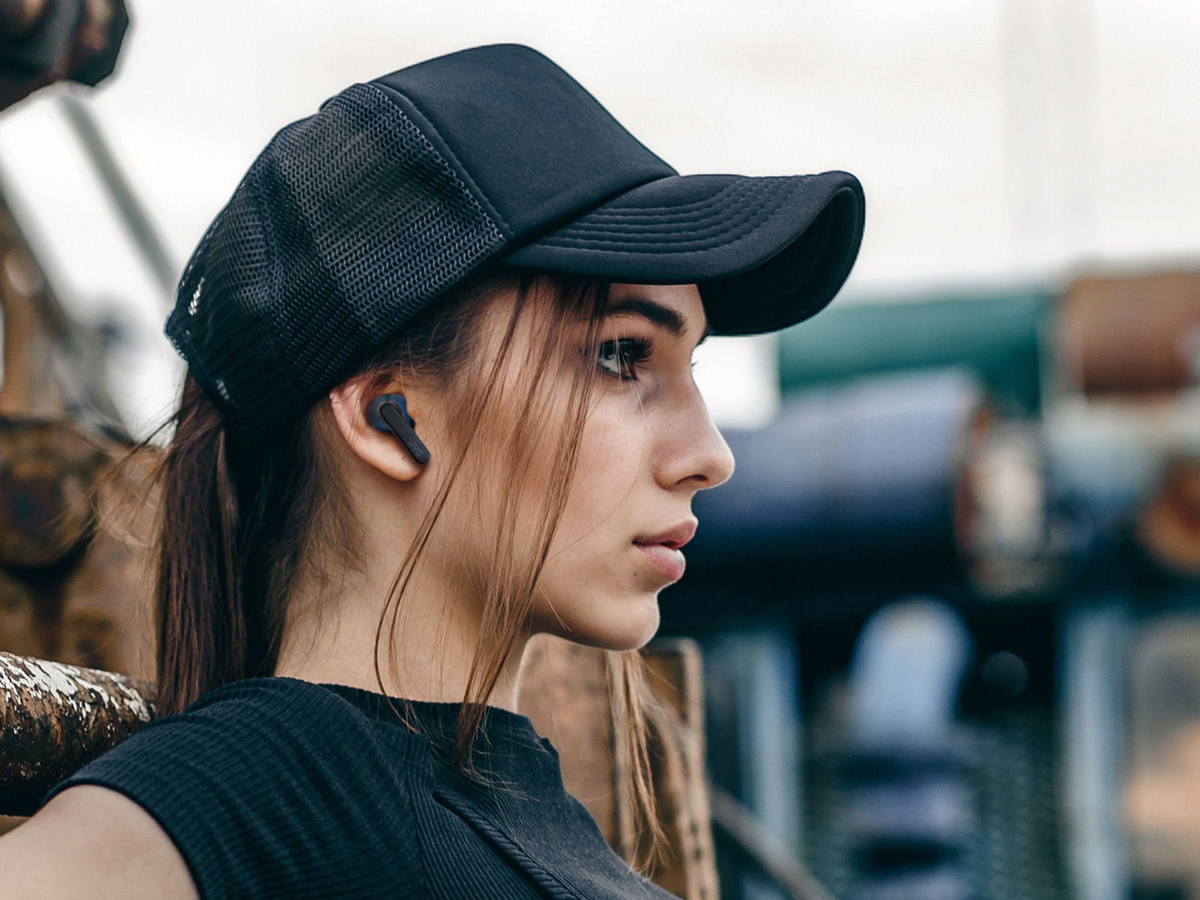 Kobieta w czapce i słuchawkach. Patrzy w bok.