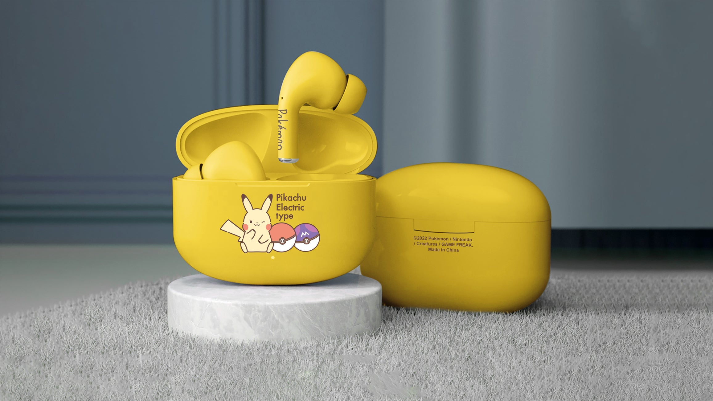 Żółte słuchawki Pokemon w żółtym etui. Etui jest otwarte, pokazując Pikachu i Pokeballa. Białe tło.